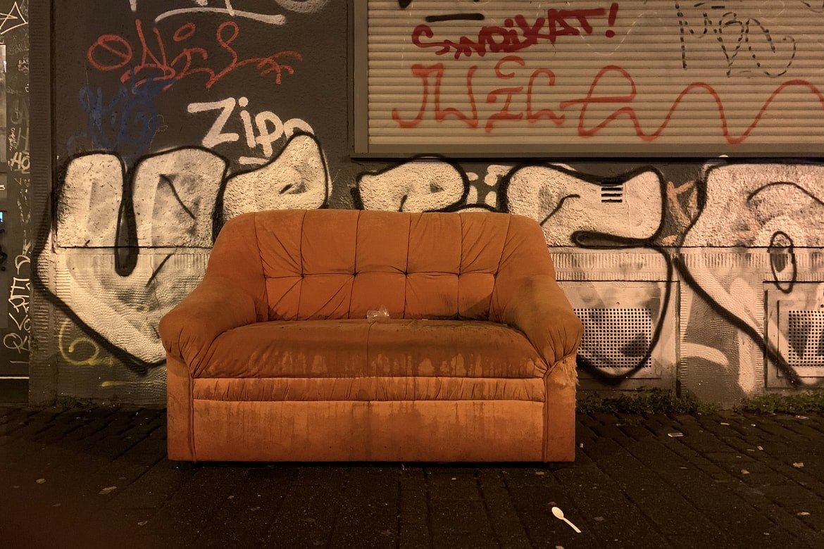 Viejo y deteriorado sofá naranja en medio de una calle. | Foto: Unsplash