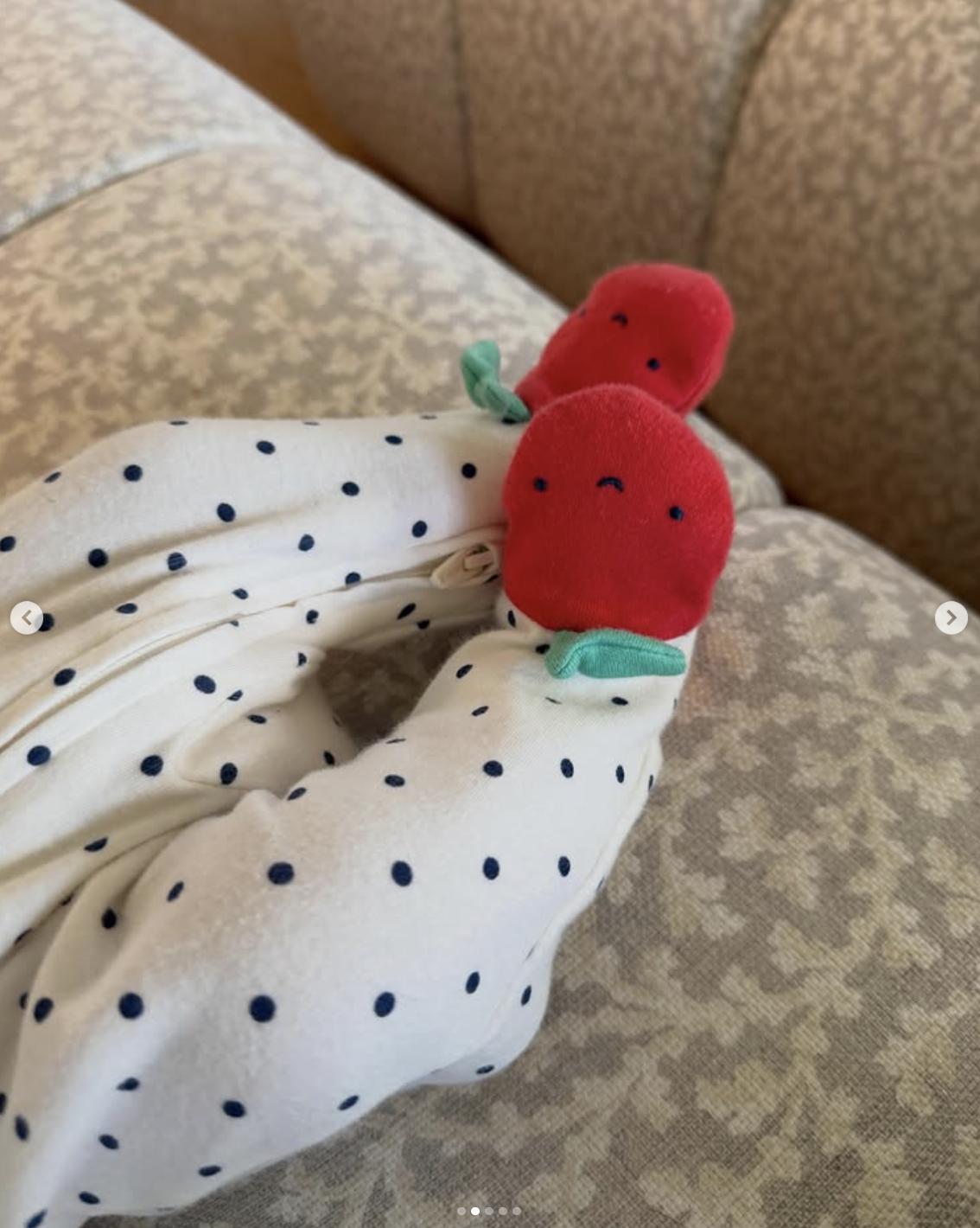 "Hailee Steinfeld and Josh Allen's baby wearing a polka-dot outfit with strawberry details while resting on a couch | Source: Instagram/haileesteinfeld