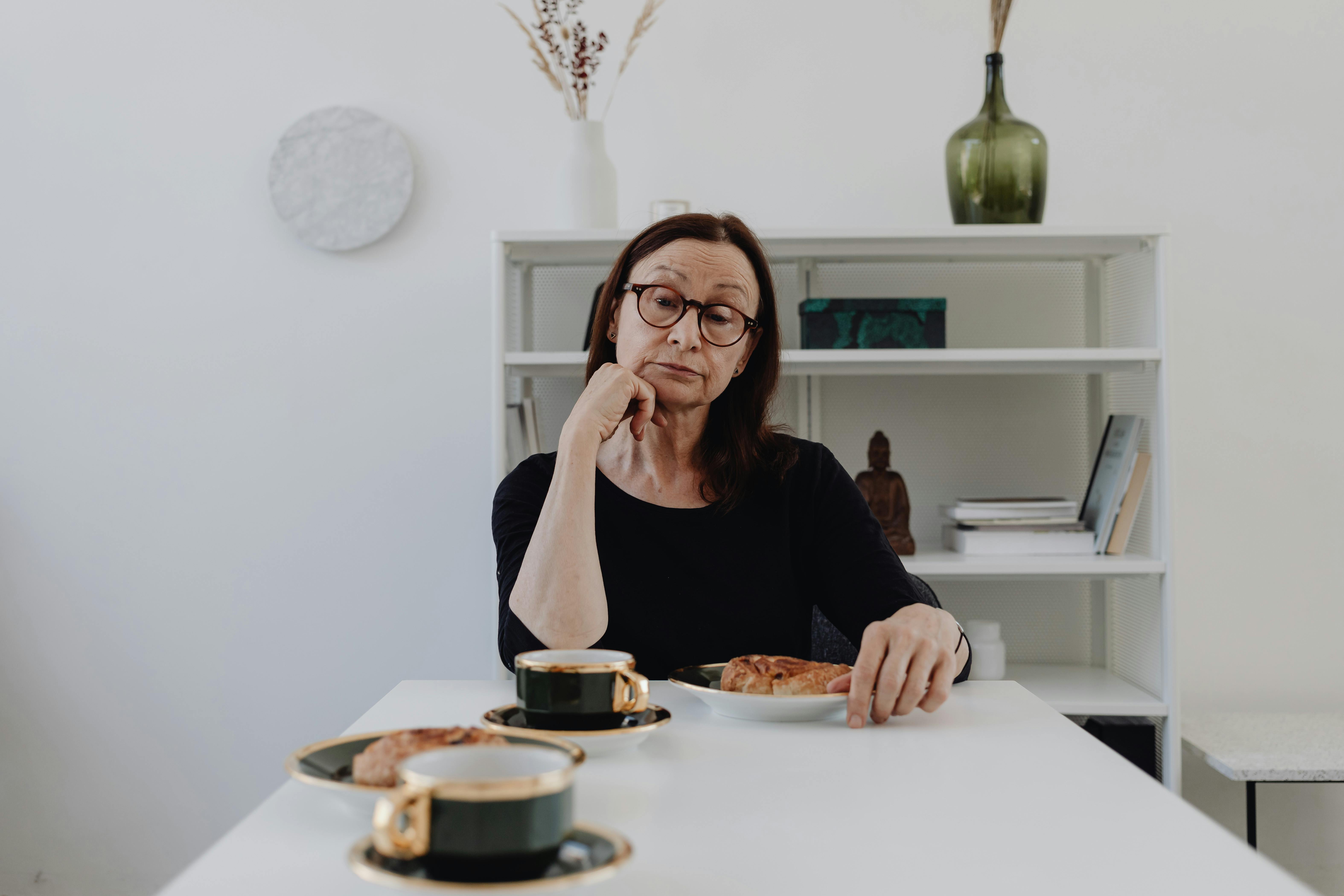 An unbothered older woman sitting at a table with food | Source: Pexels