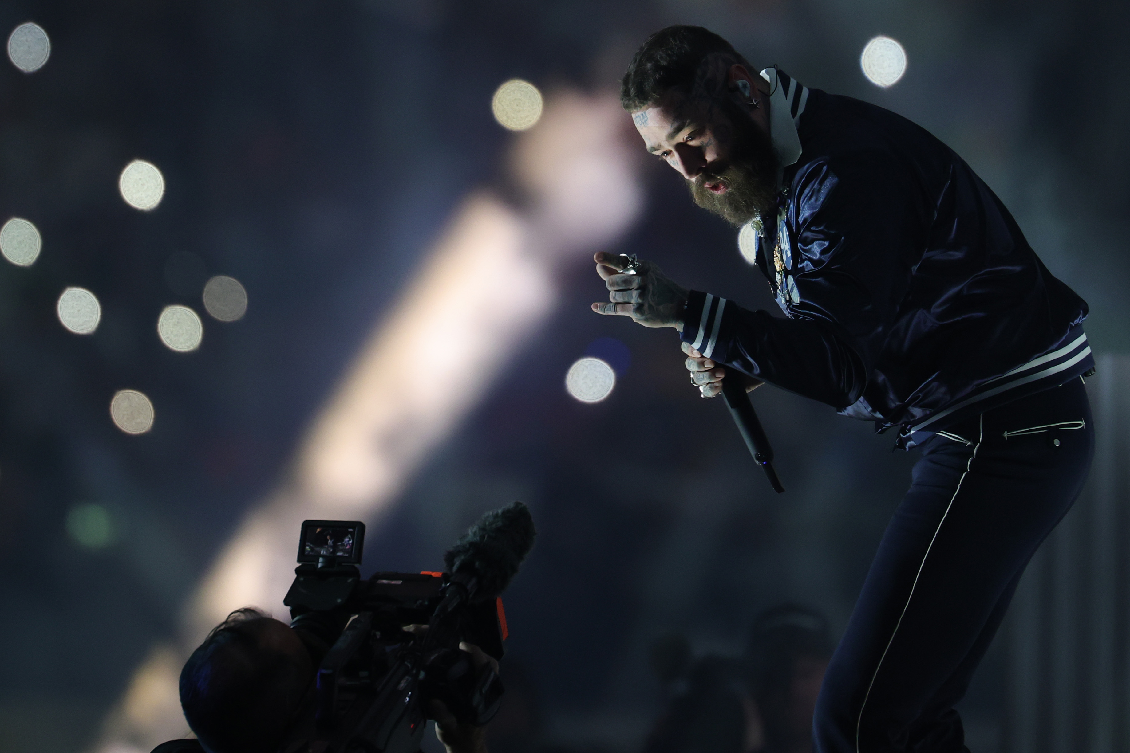 Post Malone leans forward while singing during his halftime performance at the Cowboys vs. Chiefs Thanksgiving game November 27, 2025 | Source: Getty Images