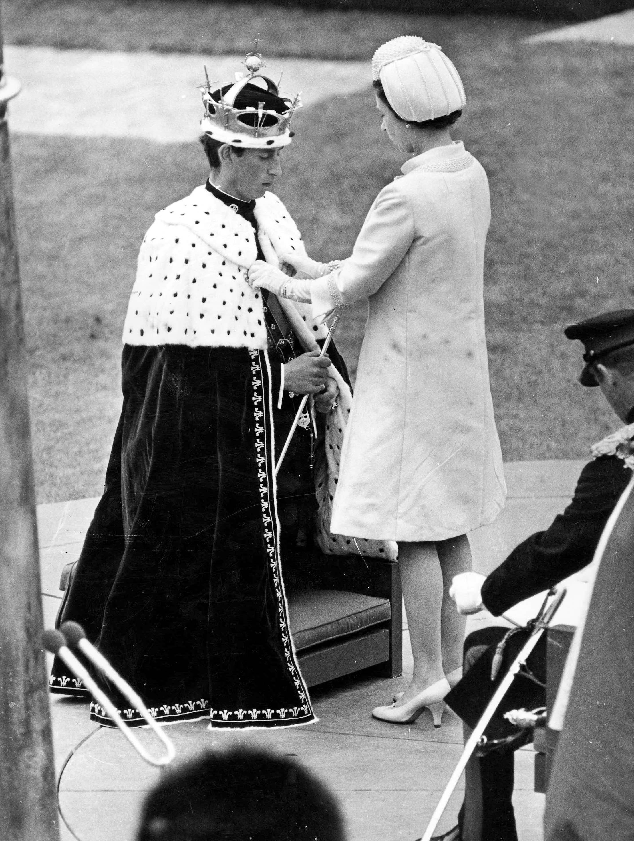 Queen Elizabeth II fastened the ermine mantle around the shoulders of Prince Charles at Caerarvon Castle, during the investiture of Prince Charles as Prince of Wales,in July 1969 | Source: Getty Images