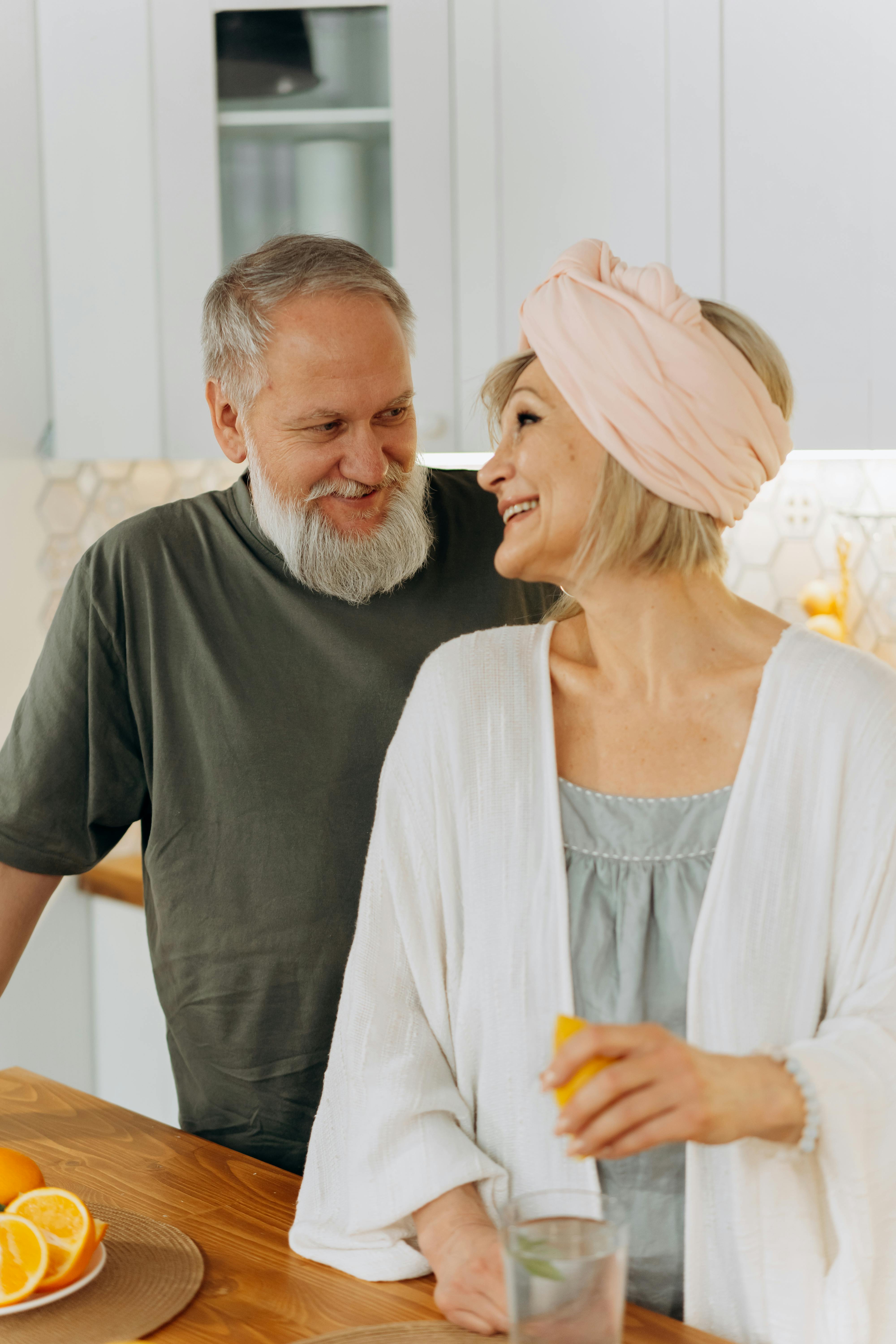 A couple smiles at each other while standing together in a kitchen. | Source: Pexels