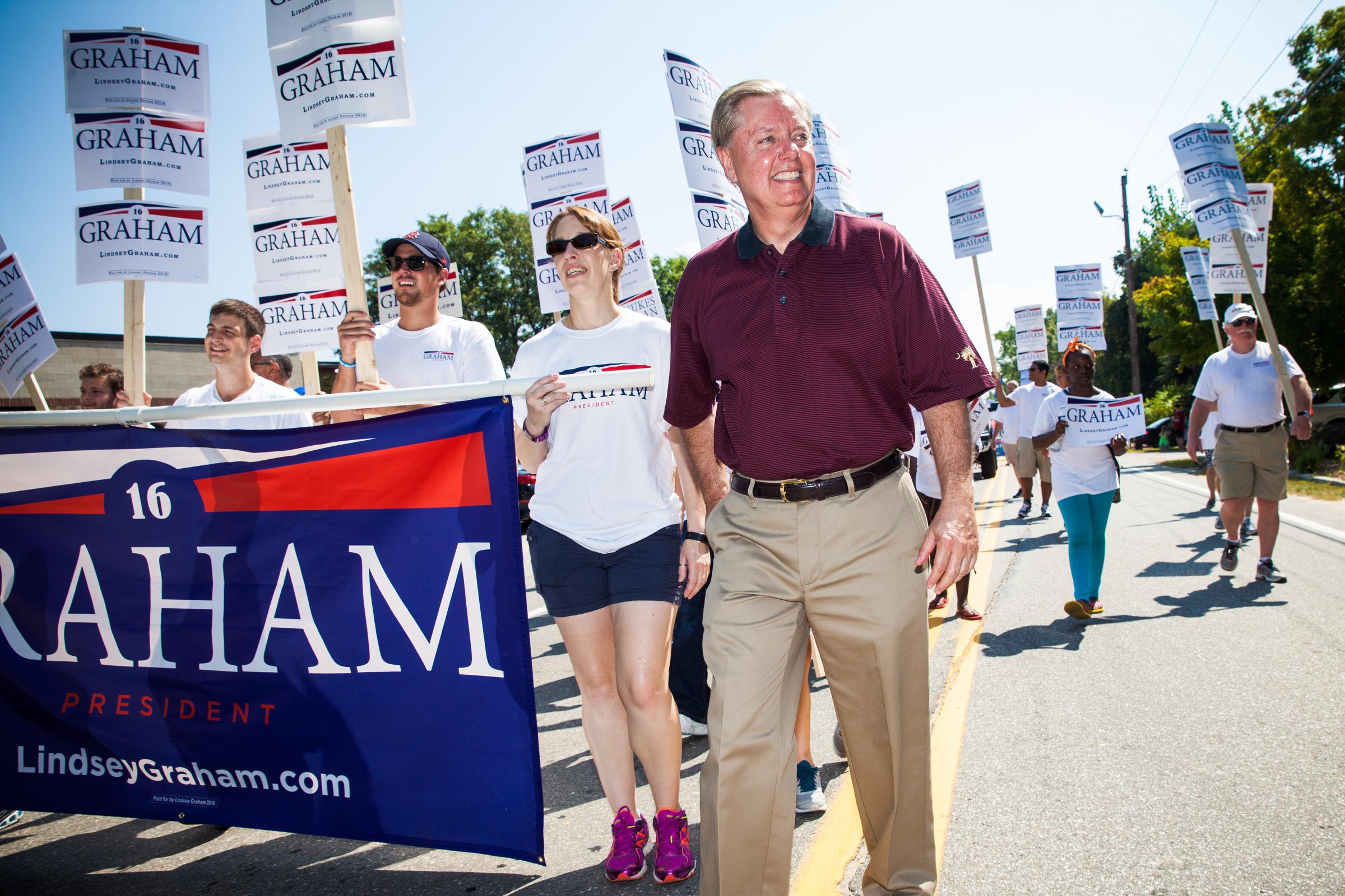 Then-presidential candidate Lindsey Graham greets supporters during a Labor Day parade in Milford, New Hampshire, in September 2015. During his funeral tribute, Donald Trump recalled how their rivalry during the 2016 Republican presidential primary eventually gave way to a close friendship. | Source: Getty Images