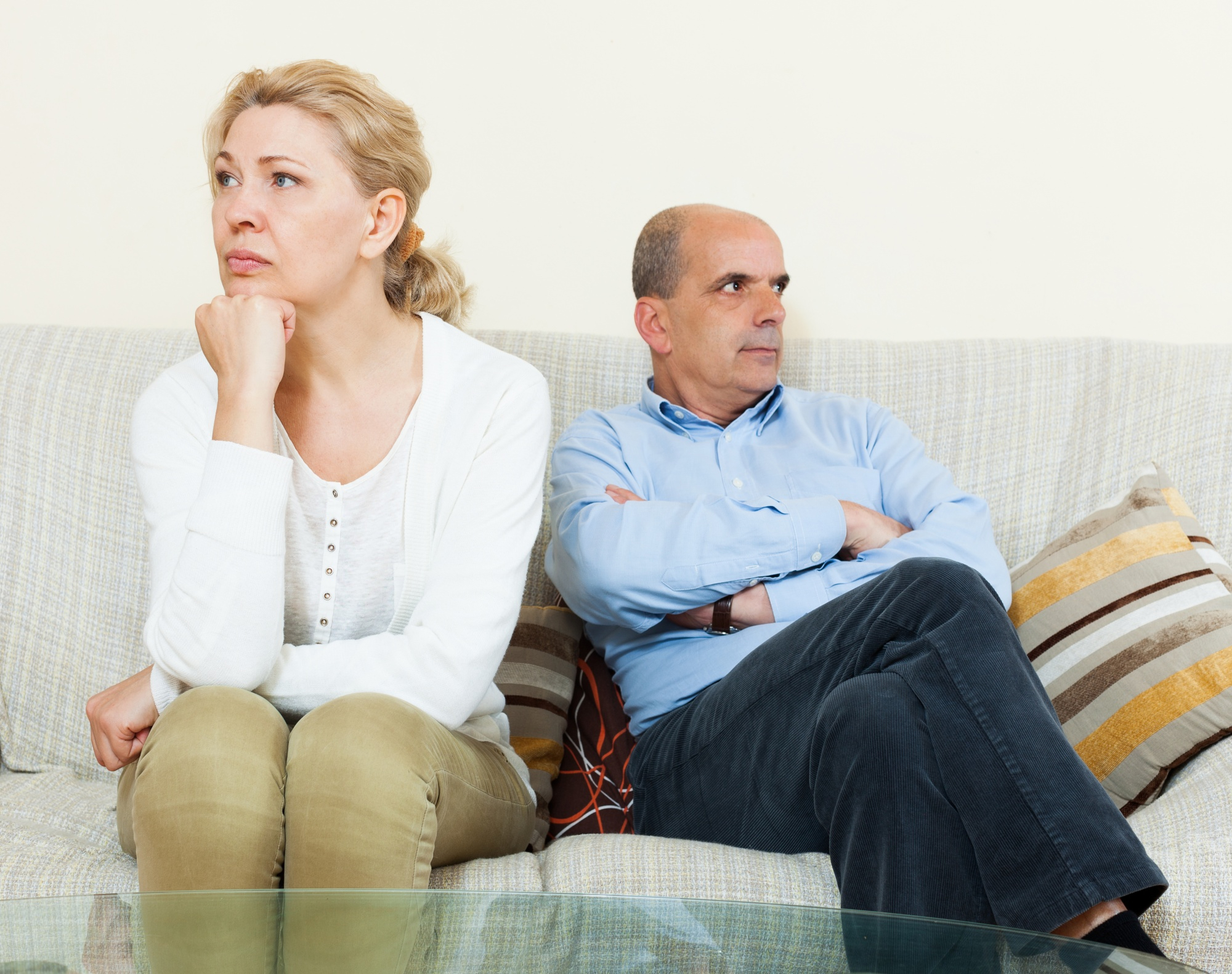 A middle-aged couple not speaking while seated on a couch | Source: Freepik