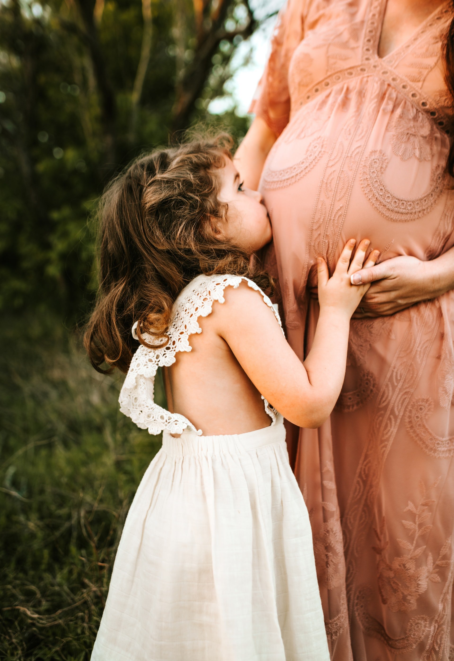 Child kissing pregnant woman's belly | Source: Unsplash