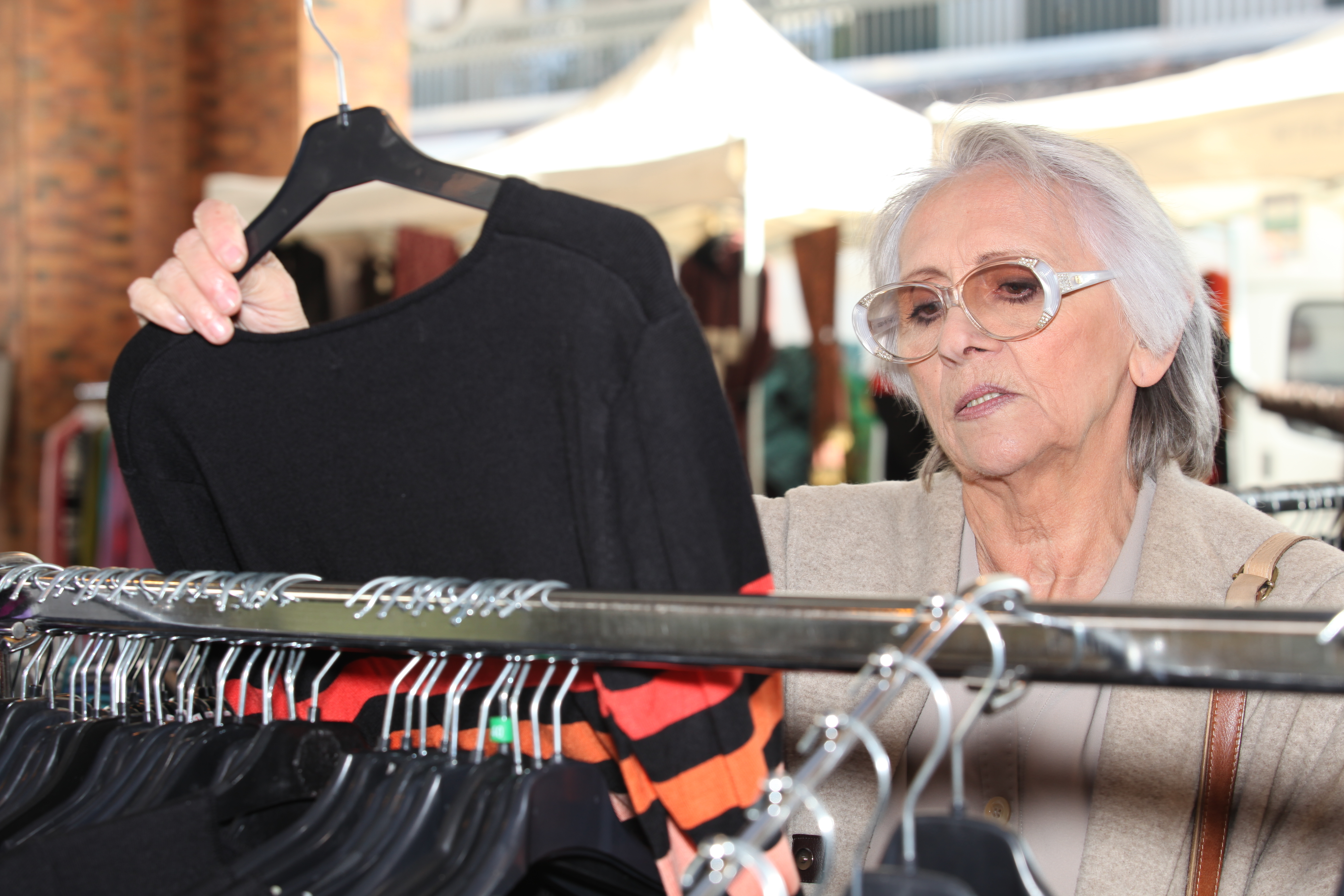 An older woman looks at the dress in the shop | Source: Shutterstock