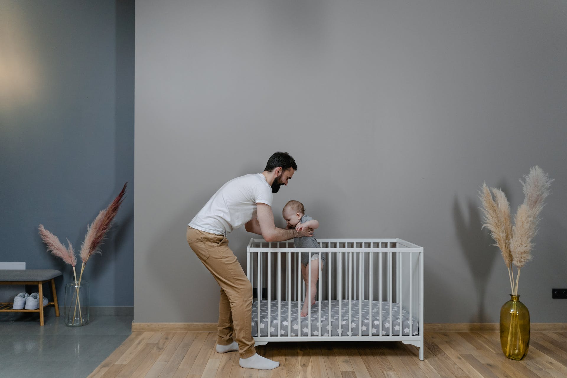 A man holding a child in a crib | Source: Pexels
