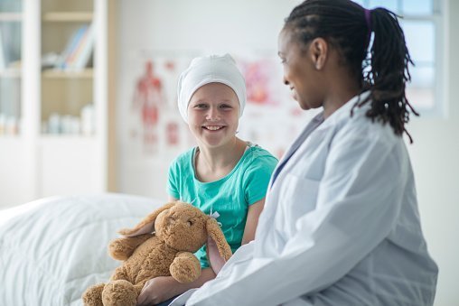 A doctor is talking with a young girl who has cancer during her appointment. | Photo: Getty Images