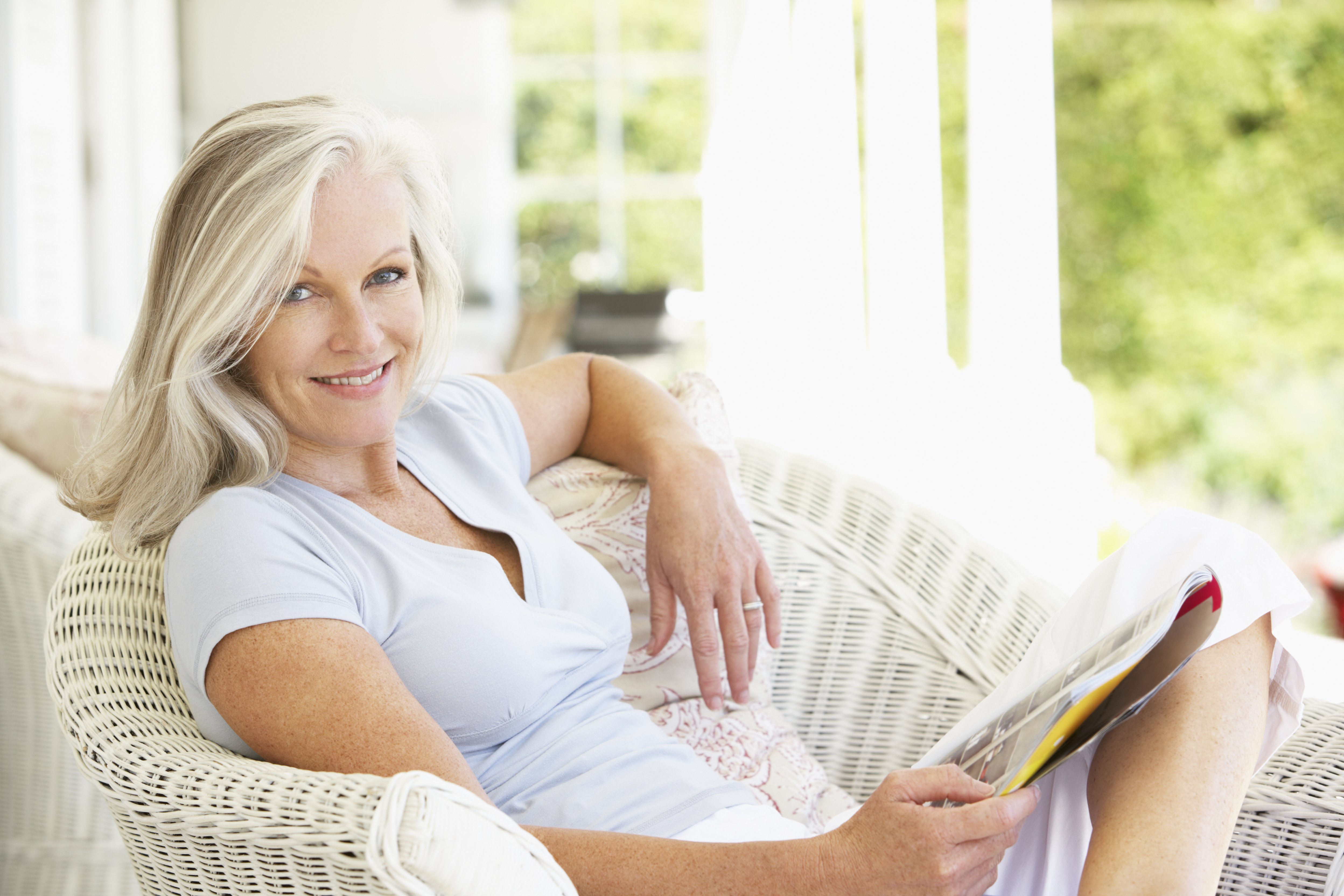 Ältere Frau, die draußen sitzt und Magazin liest | Quelle: Shutterstock