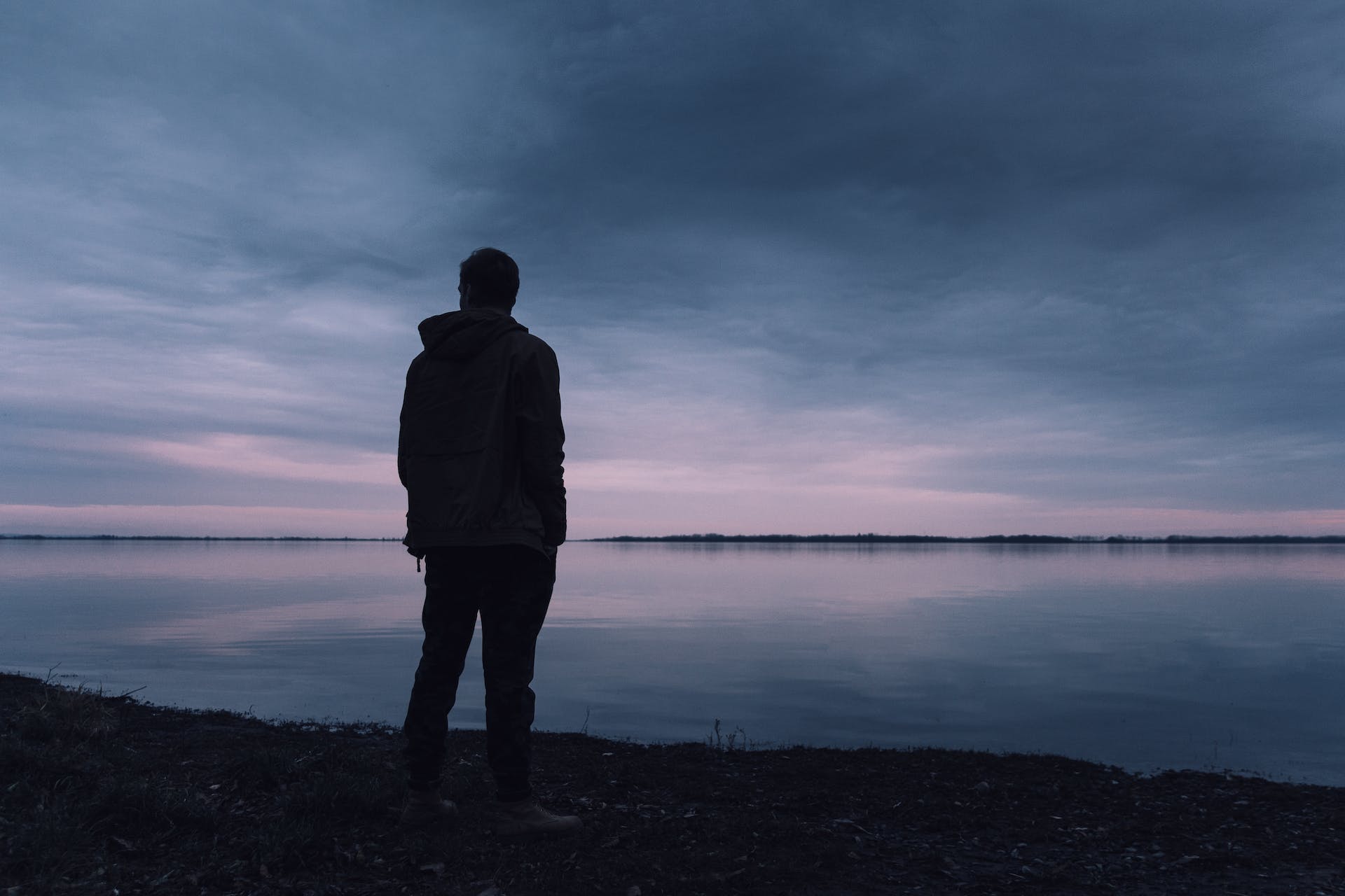 Silhouette of a man standing near a lake | Source: Pexels