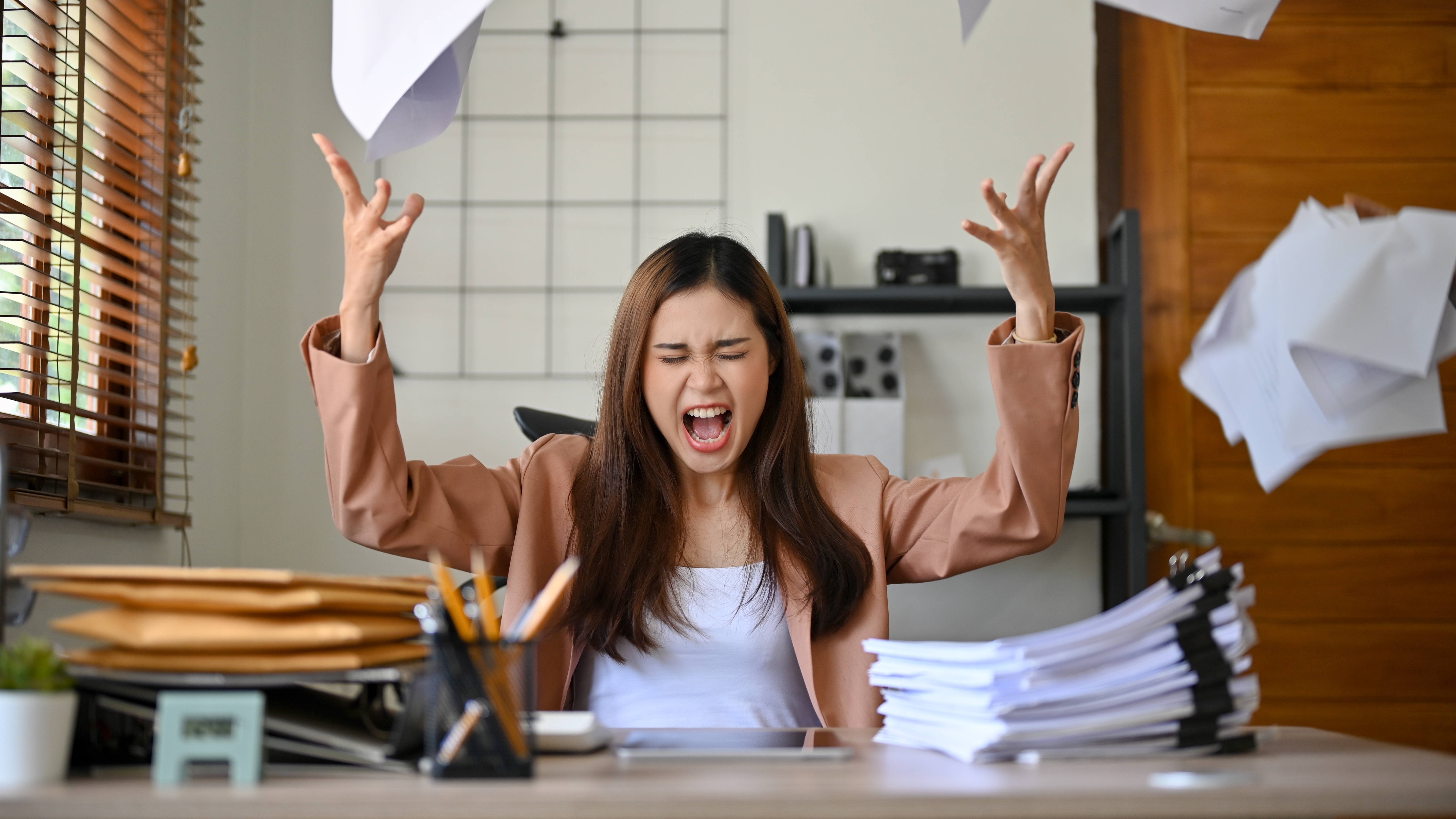 A woman tossing papers in the air in anger.  | Source: Shutterstock/BongkarnGraphic