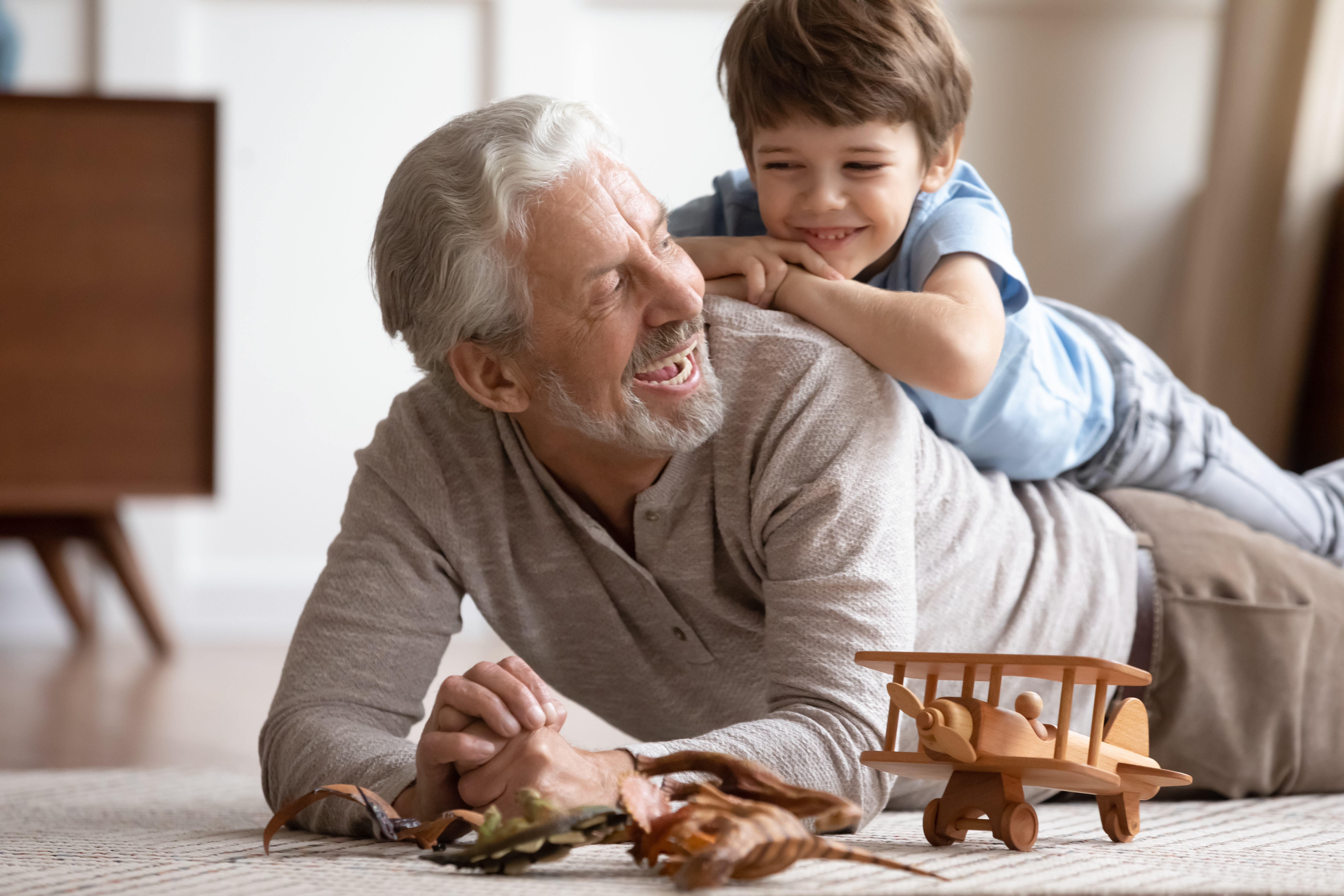 Little boy riding on his grandfather's back at home | Source: Shutterstock