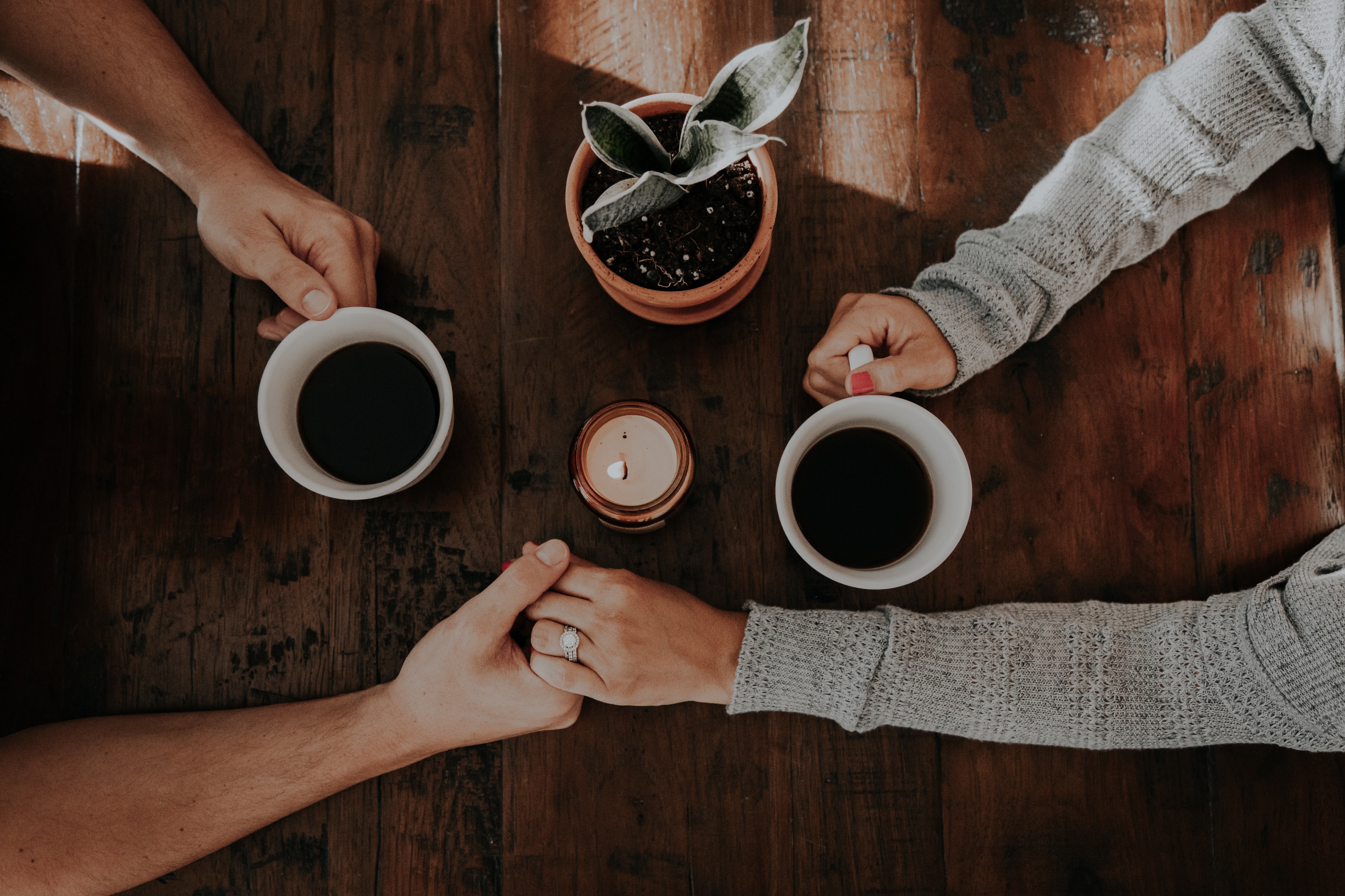 A photo of a couple holding coffee mugs while holding hands | Source: Unsplash