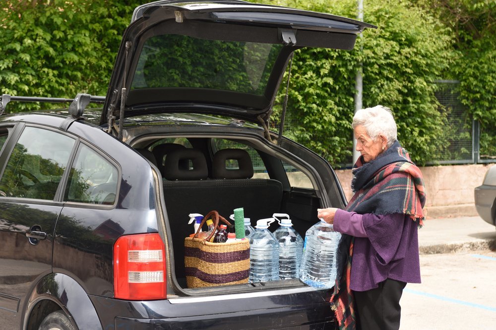 An elderly woman loading her car at a parking lot | Photo: Shutterstock