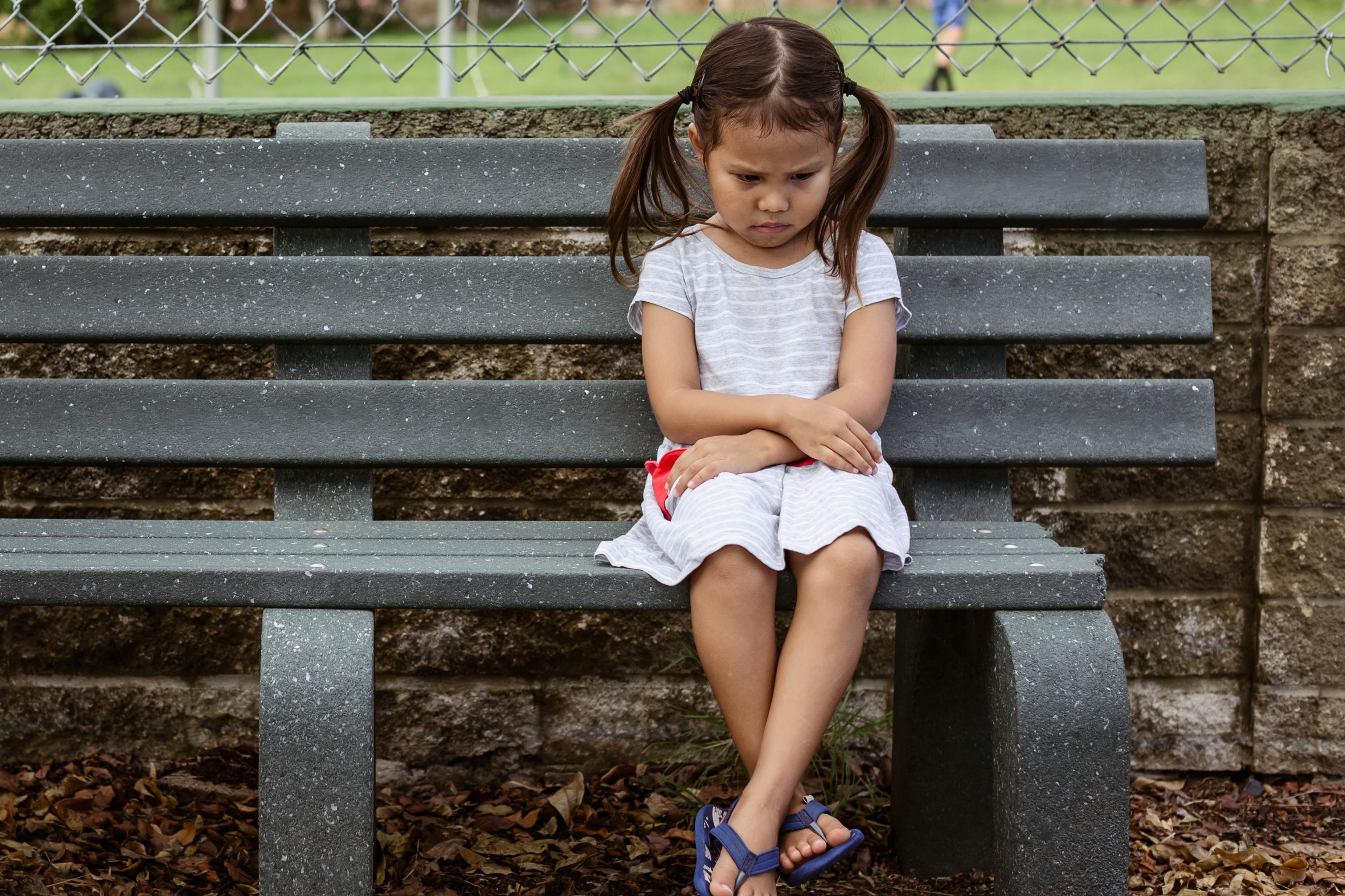 An upset little girl sitting alone on the bench | Source: Shutterstock