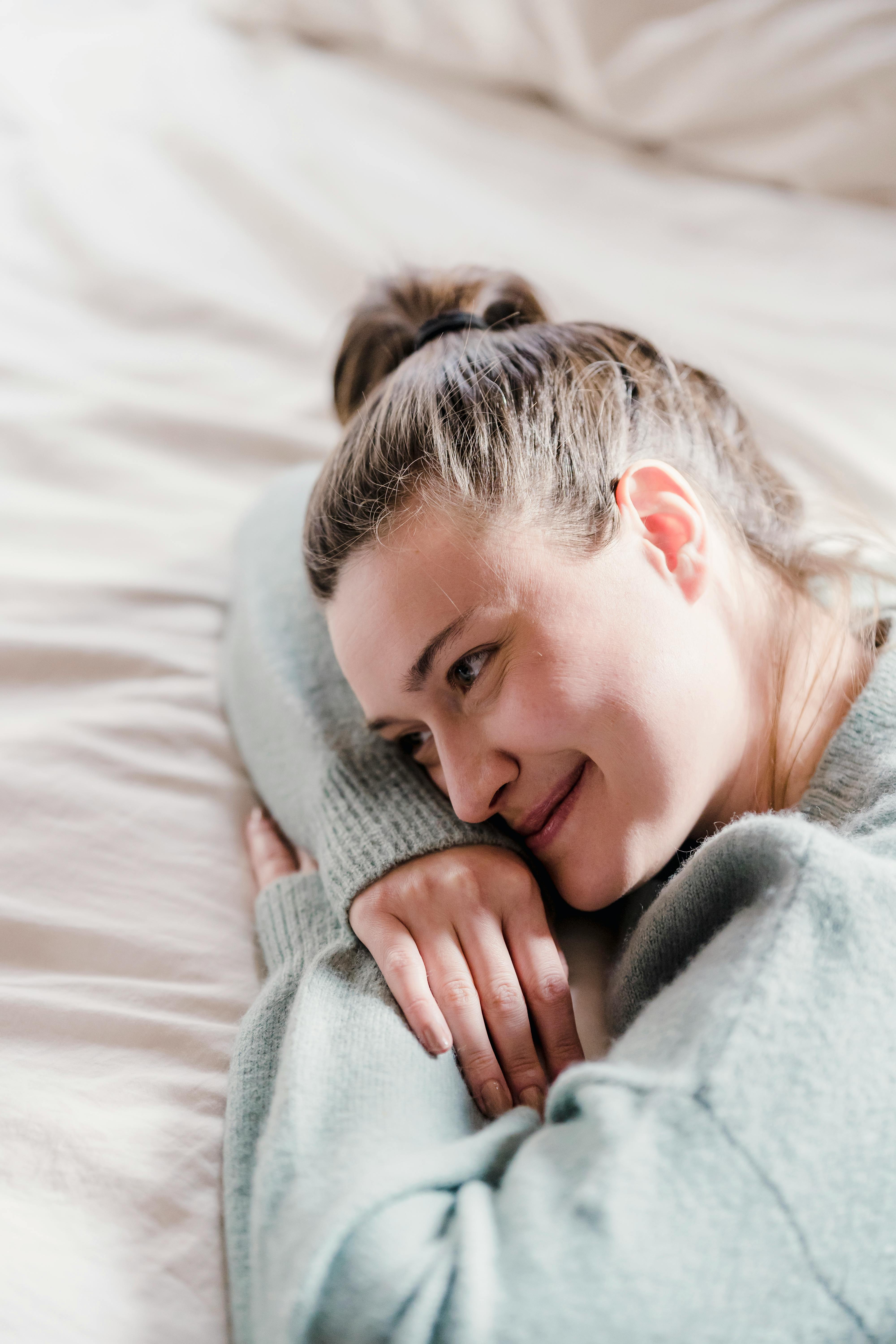 A happy woman lying on a bed while thinking | Source: Pexels