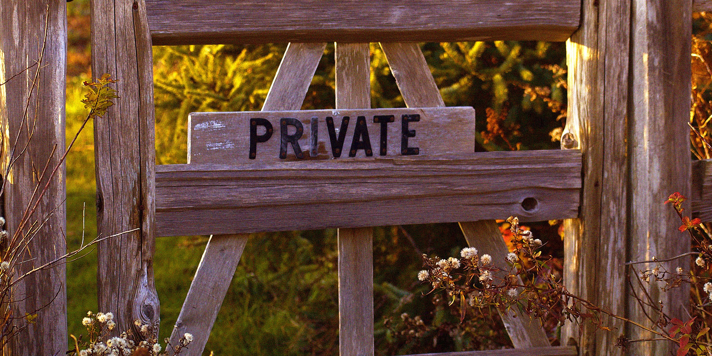 Unsplash | A wooden gate that has a sign which reads 'Private' on it
