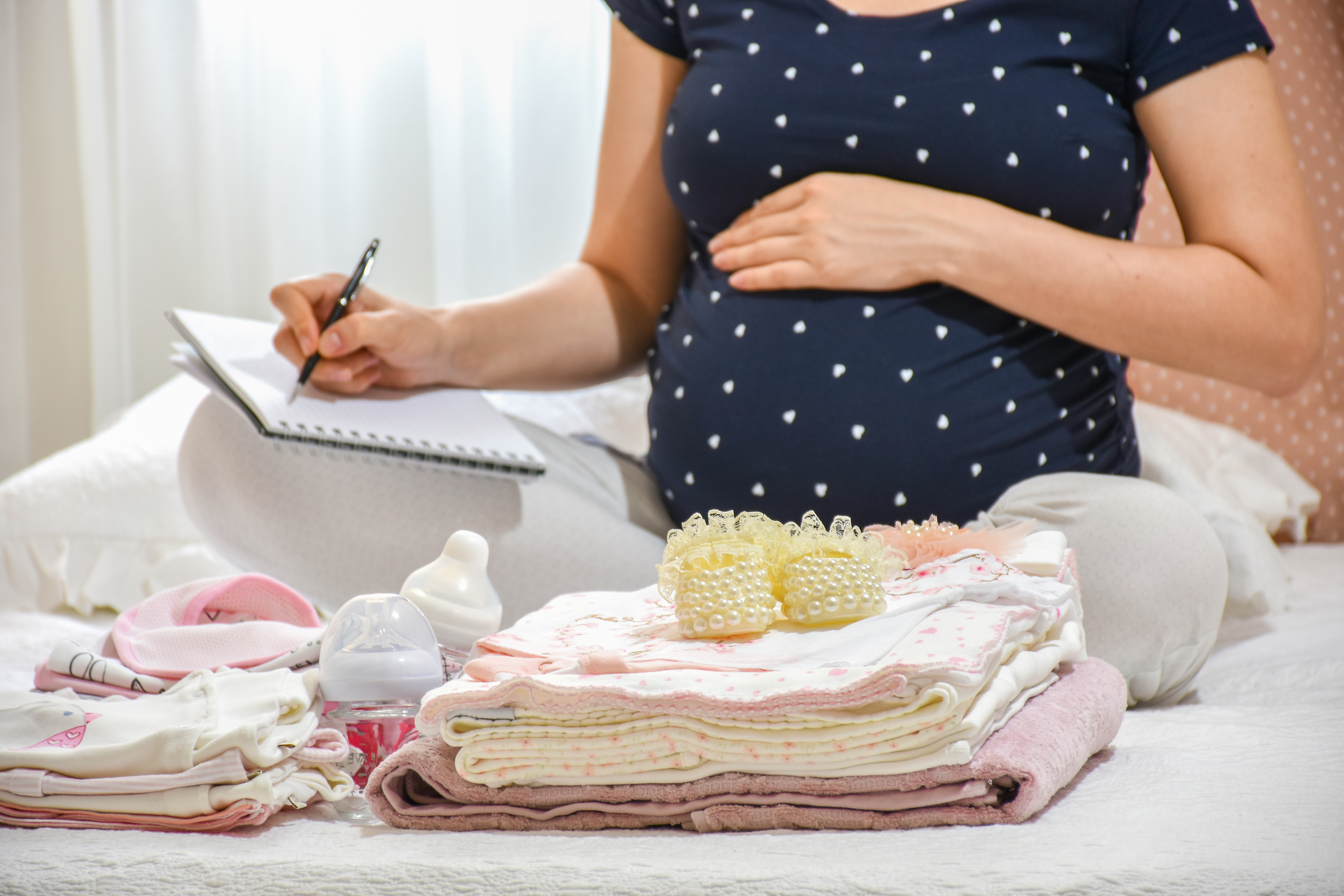 A pregnant woman with baby clothes | Source: Shutterstock