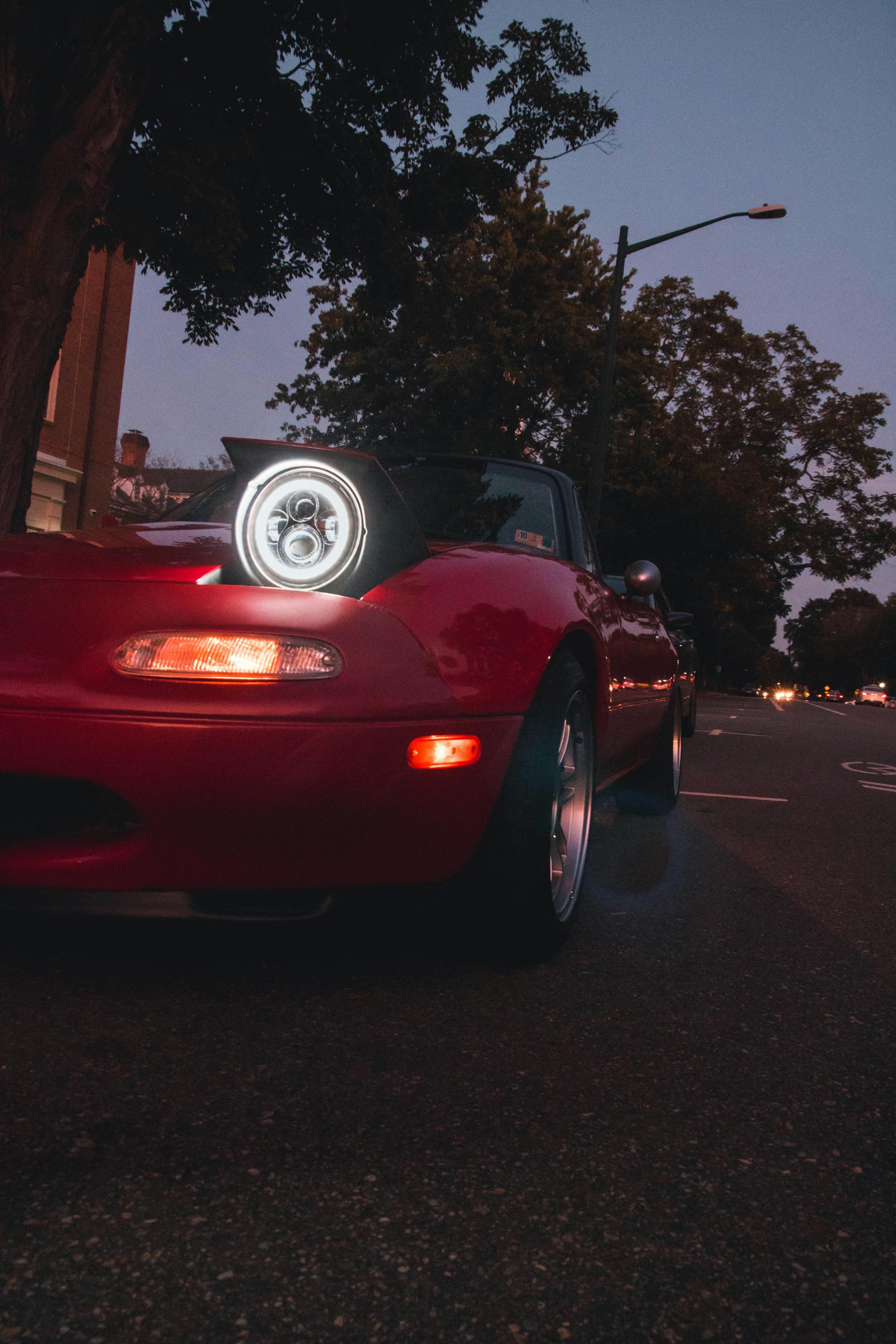 A red car with its headlights on at night | Source: Pexels