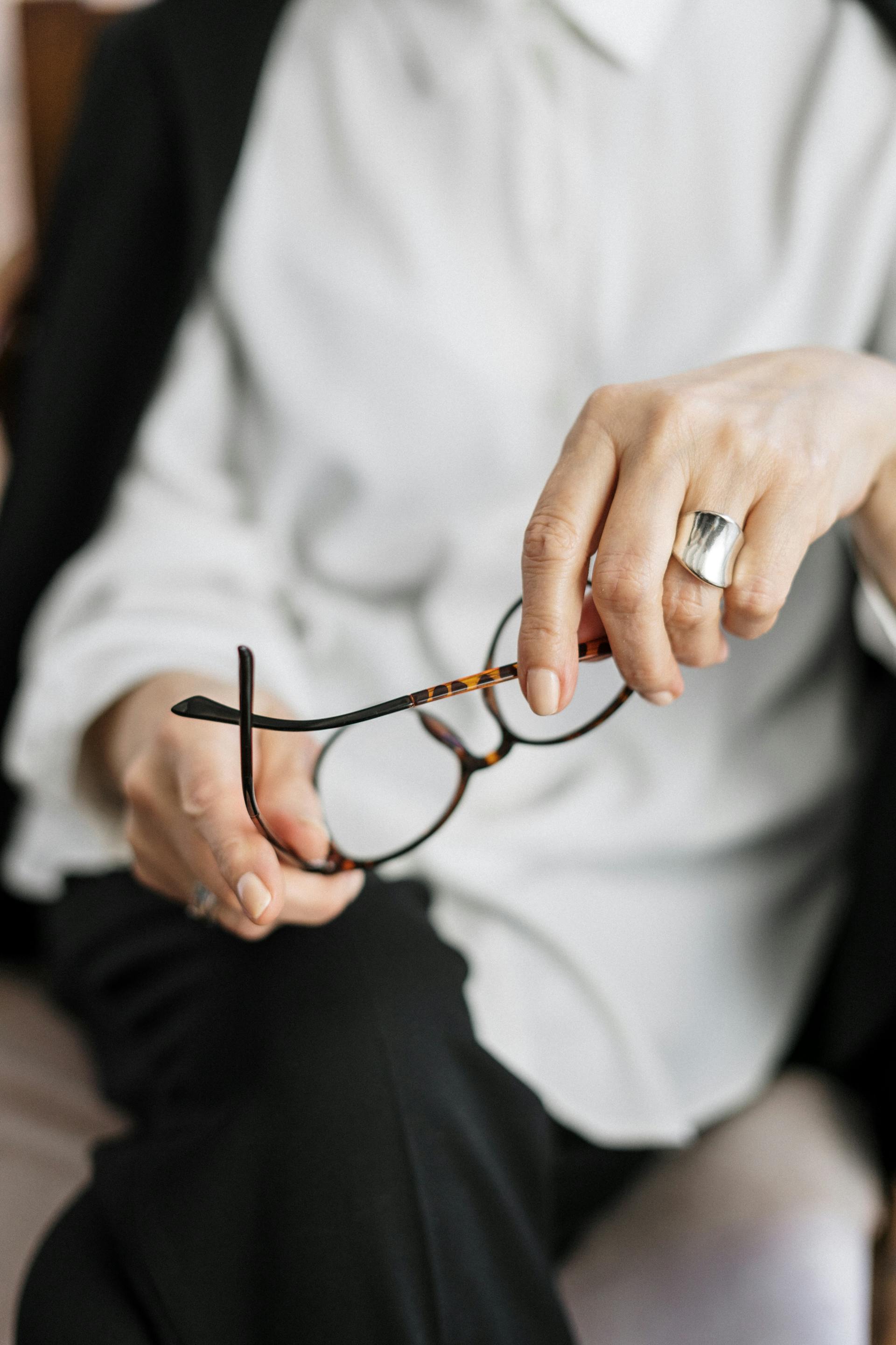 A female therapist holding her brown-framed eyeglasses | Source: Pexels