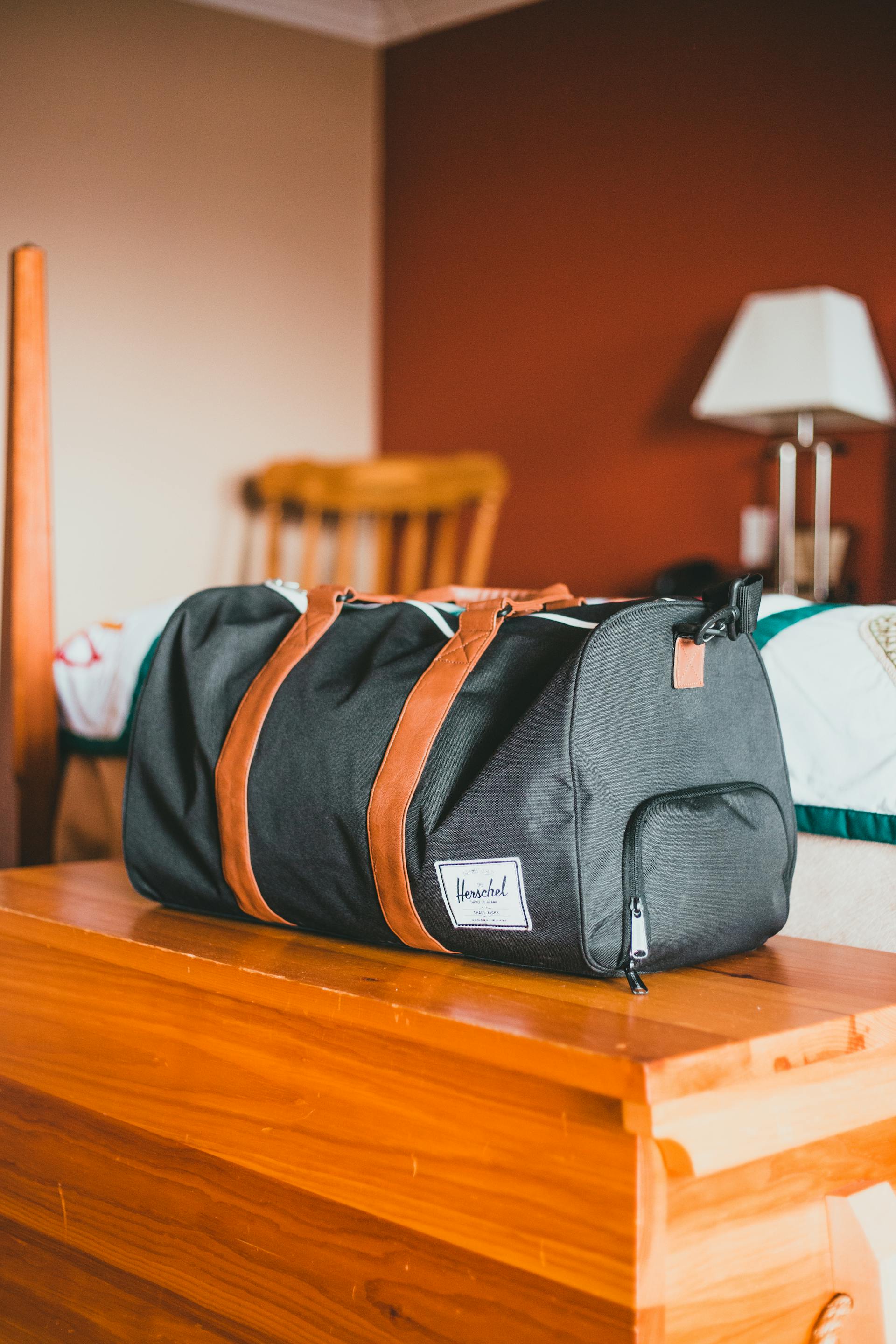 A duffel bag lying on a wooden table | Source: Pexels