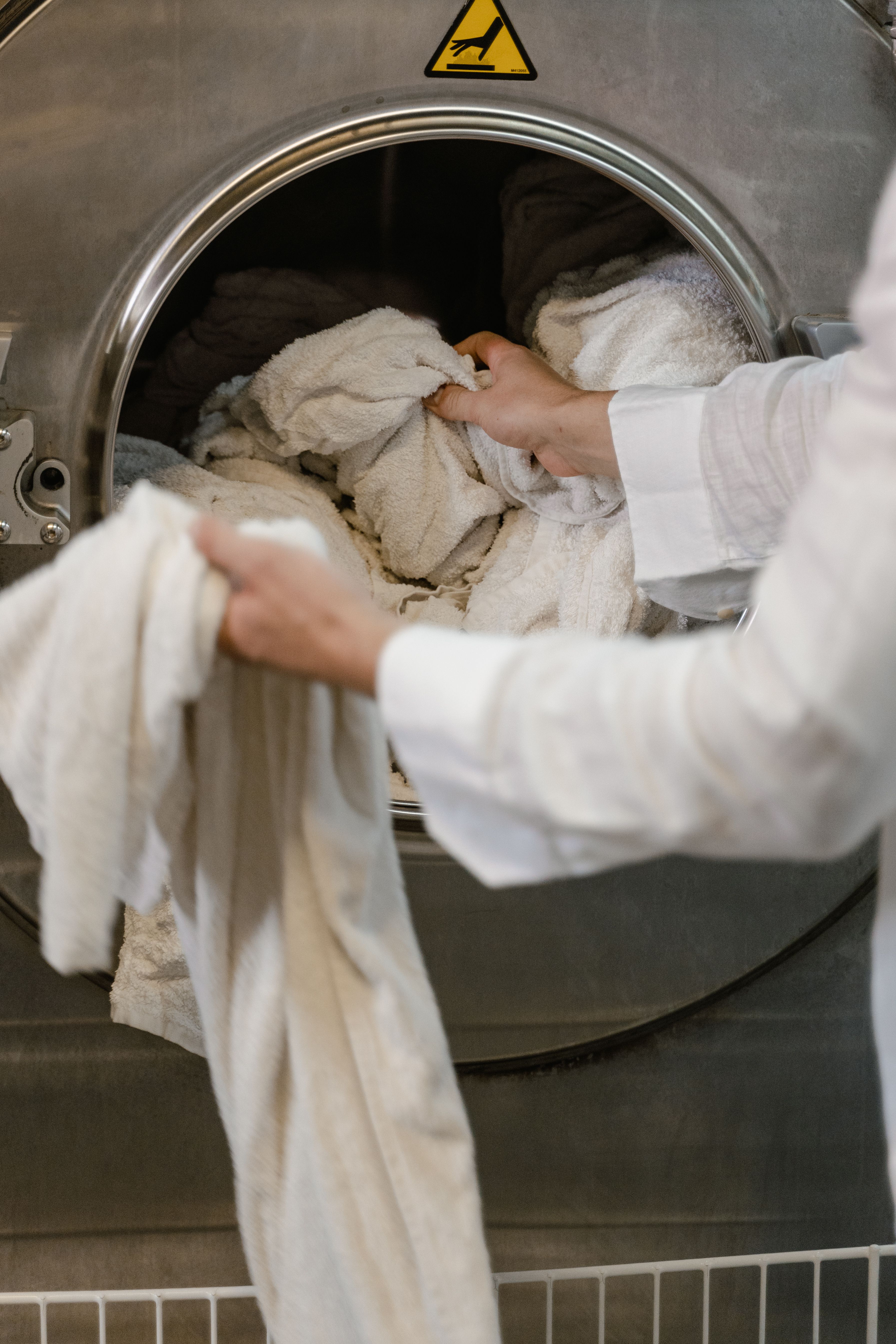 A person pulling white towels from a washing drum. | Source: Pexels