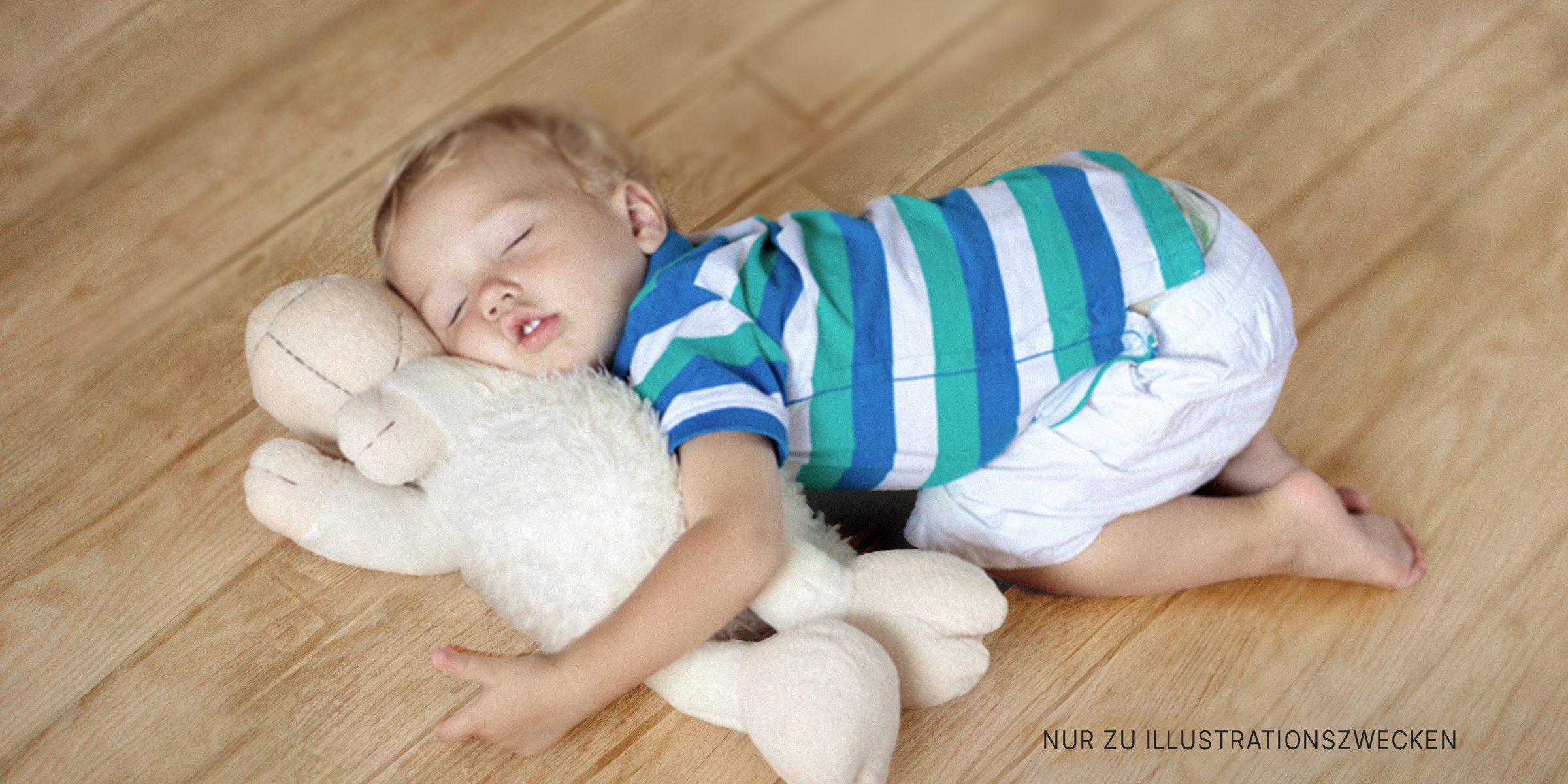 Kleinkind auf dem Boden mit Teddybär | Quelle: Shutterstock