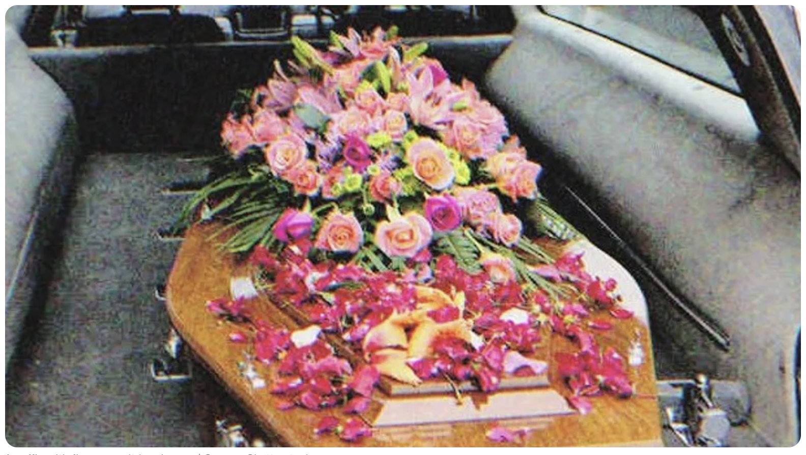 A coffin with flowers on it in a hearse | Source: Shutterstock