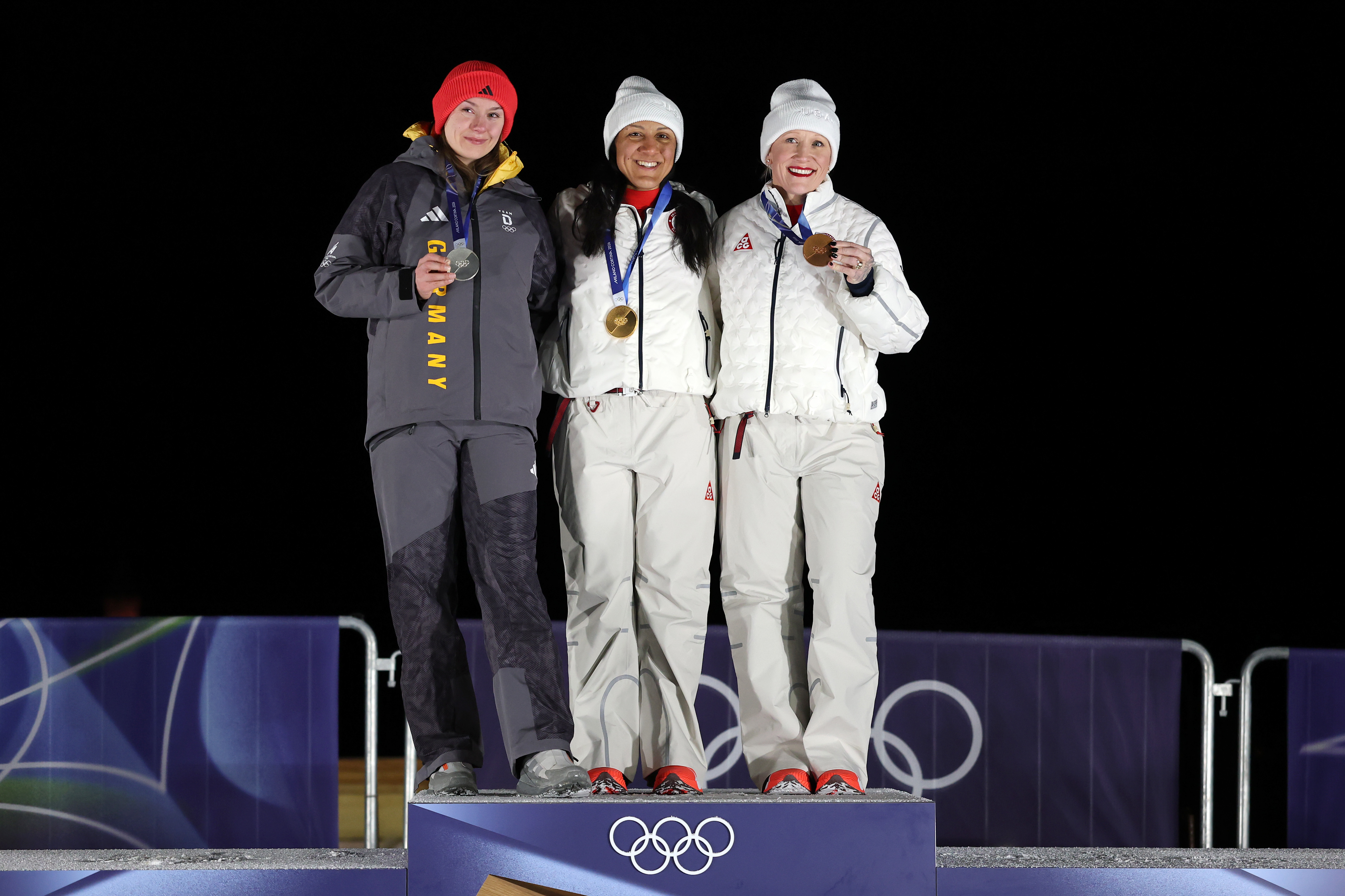 Elana Meyers Taylor (center) stands with Laura Nolte (left) and Kaillie Humphries on the podium at the 2026 Winter Olympics | Source: Getty Images
