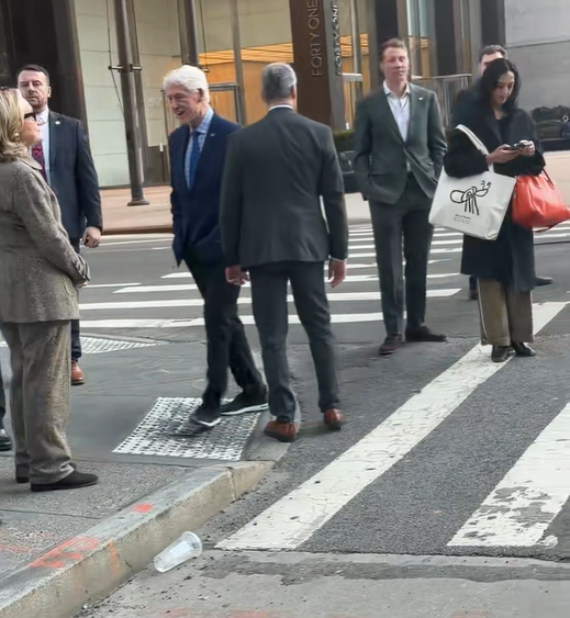 Hillary Clinton stands near the curb with her hands clasped together as Bill Clinton steps across the zebra-striped crosswalk. | Source: TikTok/elderordonez