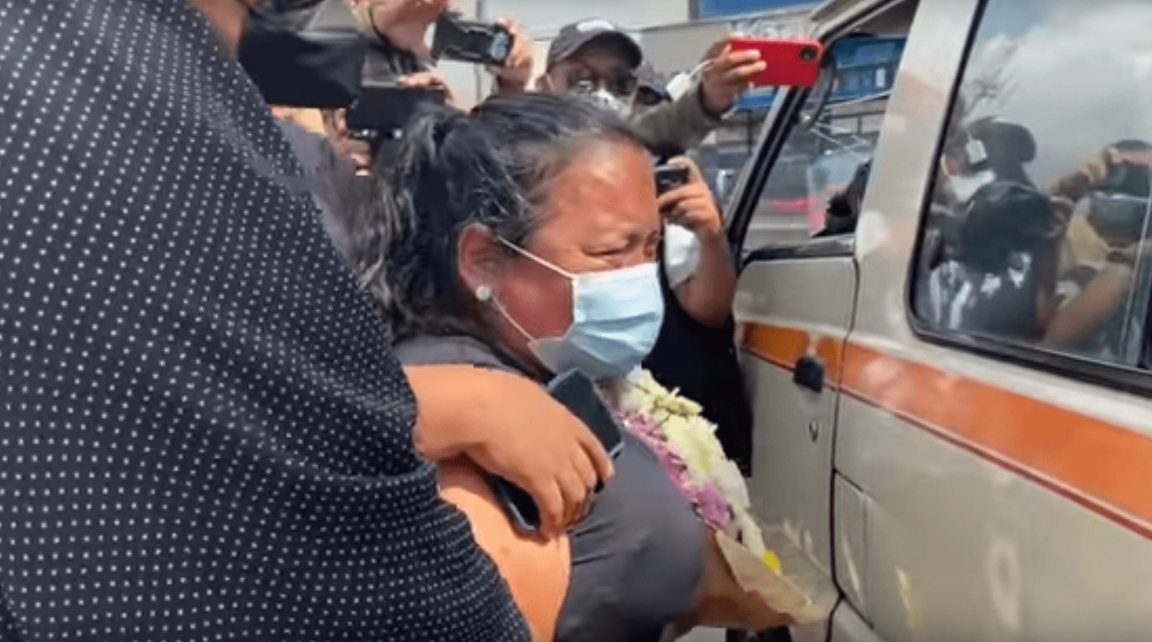 Mujer afligida llorando junto al vehículo que lleva el ataúd de su fallecido esposo. | Foto: YouTube/Guatevisión 