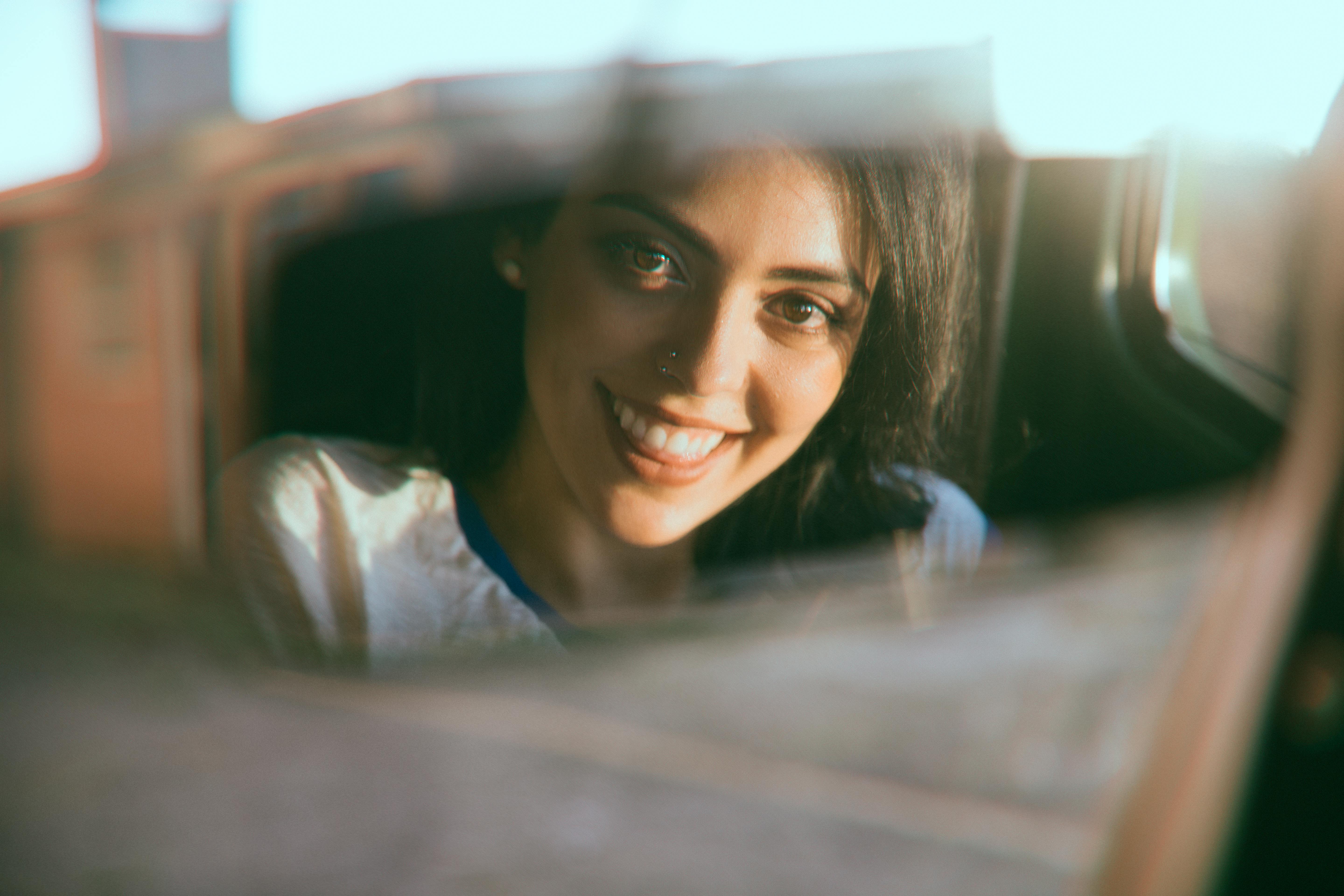 A happy woman looking at the rearview mirror while driving | Source: Pexels