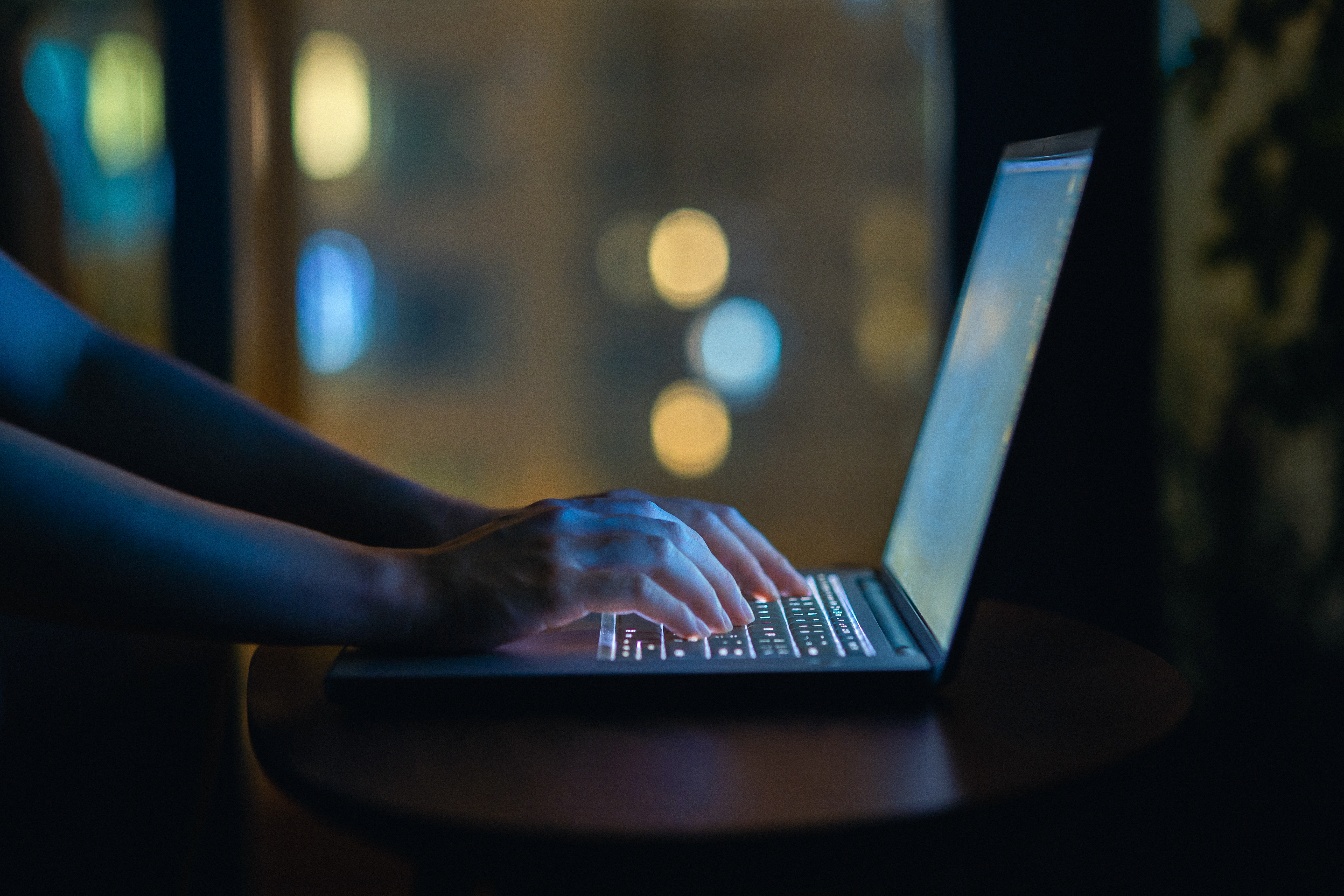 Cropped shot of woman's hand typing on computer keyboard in the dark, working late on laptop at home | Source: Getty Images
