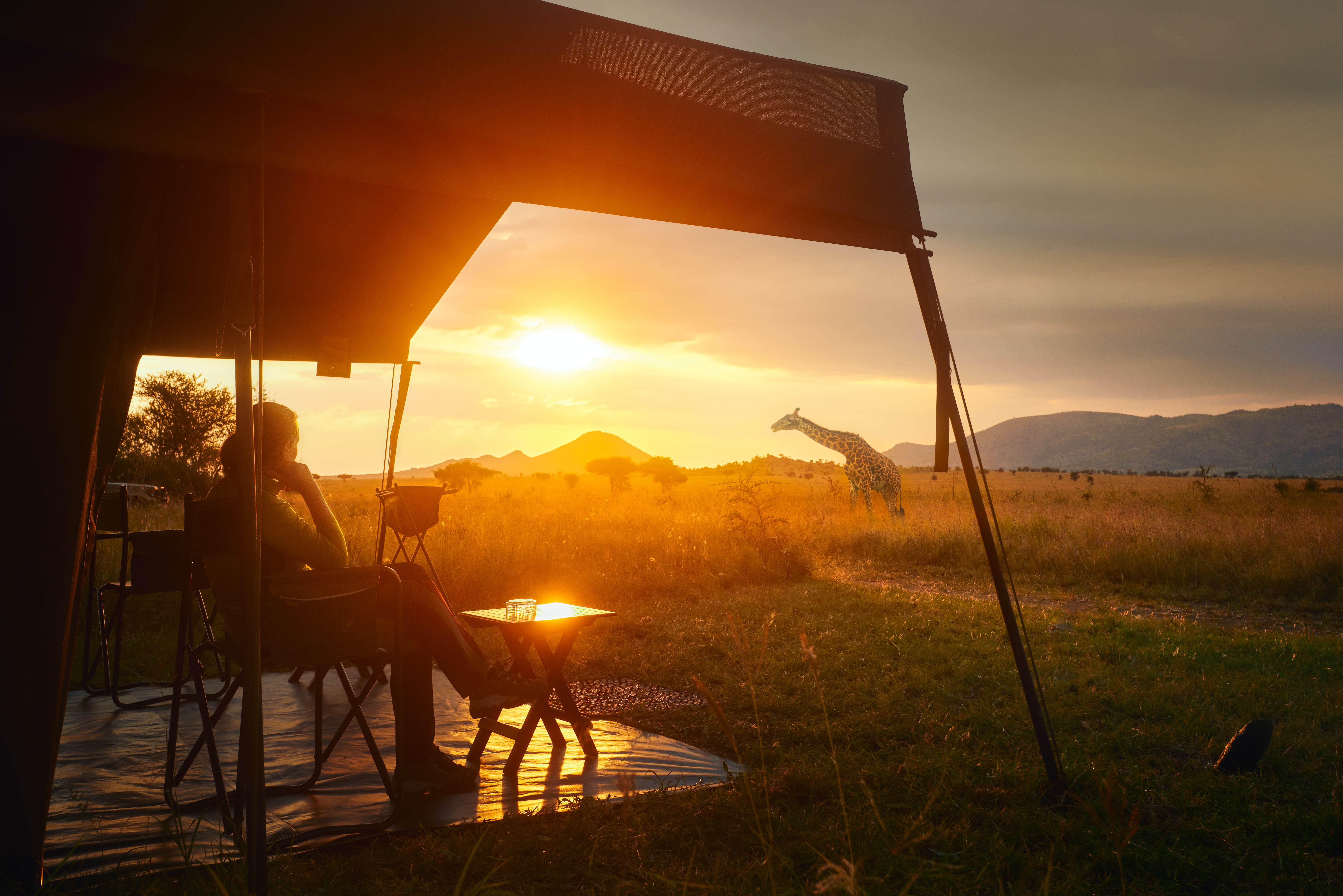 A woman relaxing at a safari lodge with a giraffe in the background | Source: Shutterstock