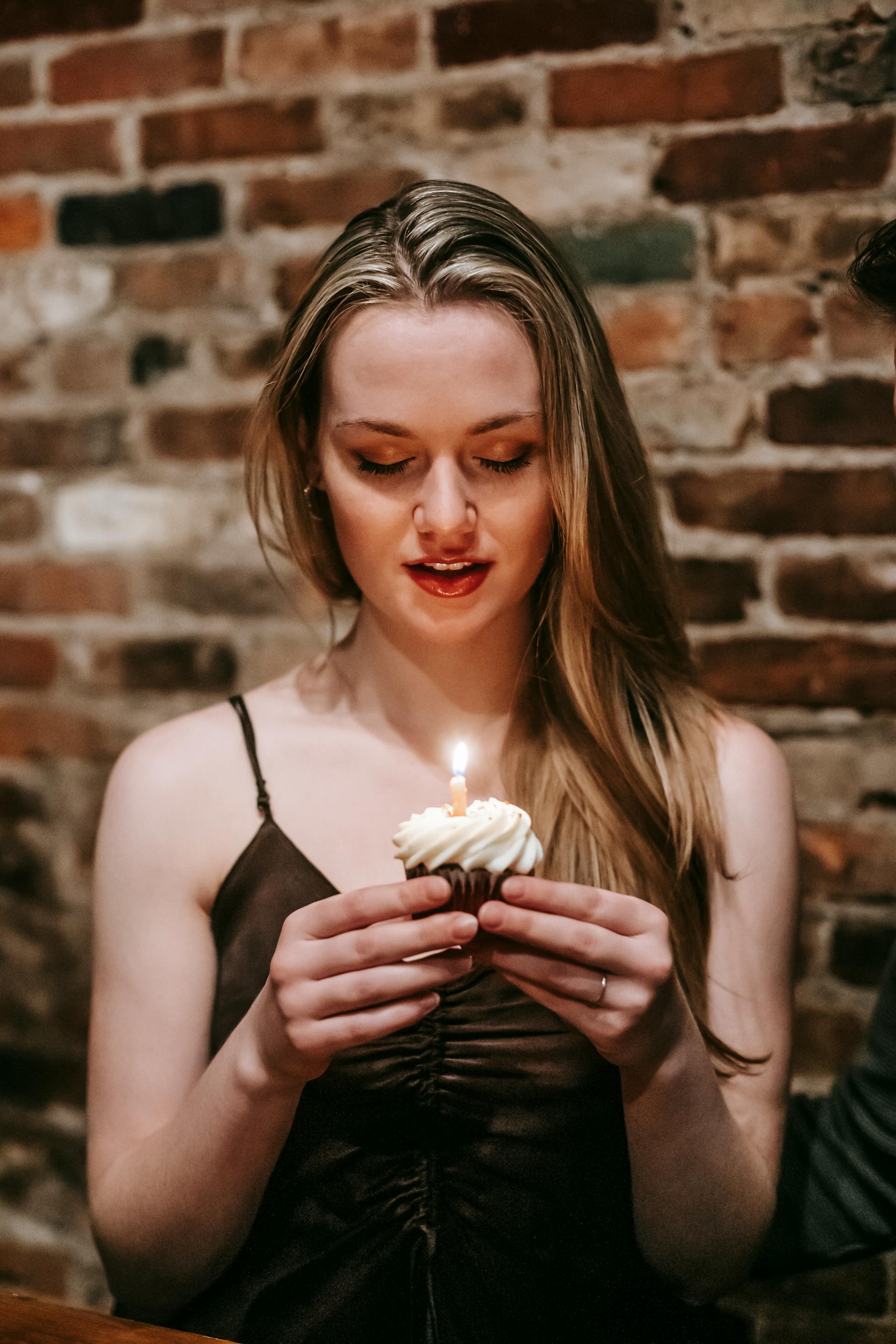 A woman holding a cupcake with a candle | Source: Pexels
