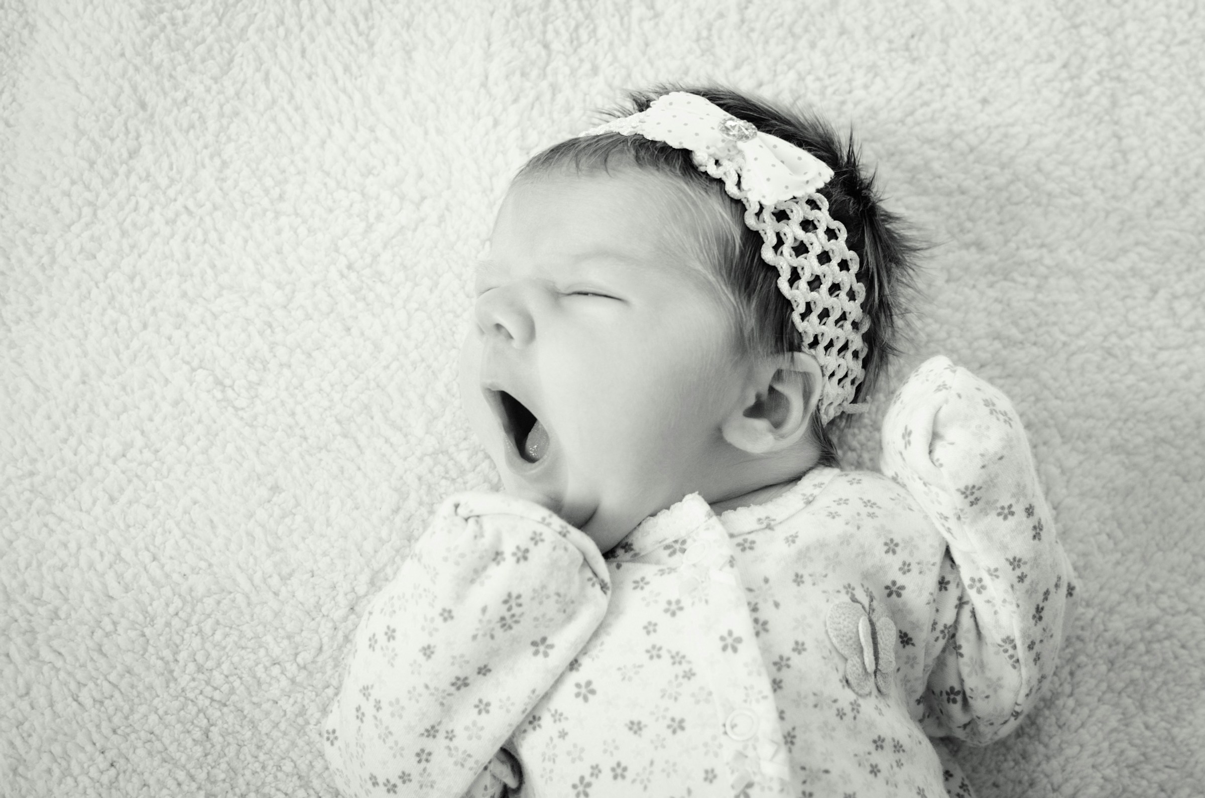 Grayscale shot of a newborn baby girl yawning | Source: Unsplash