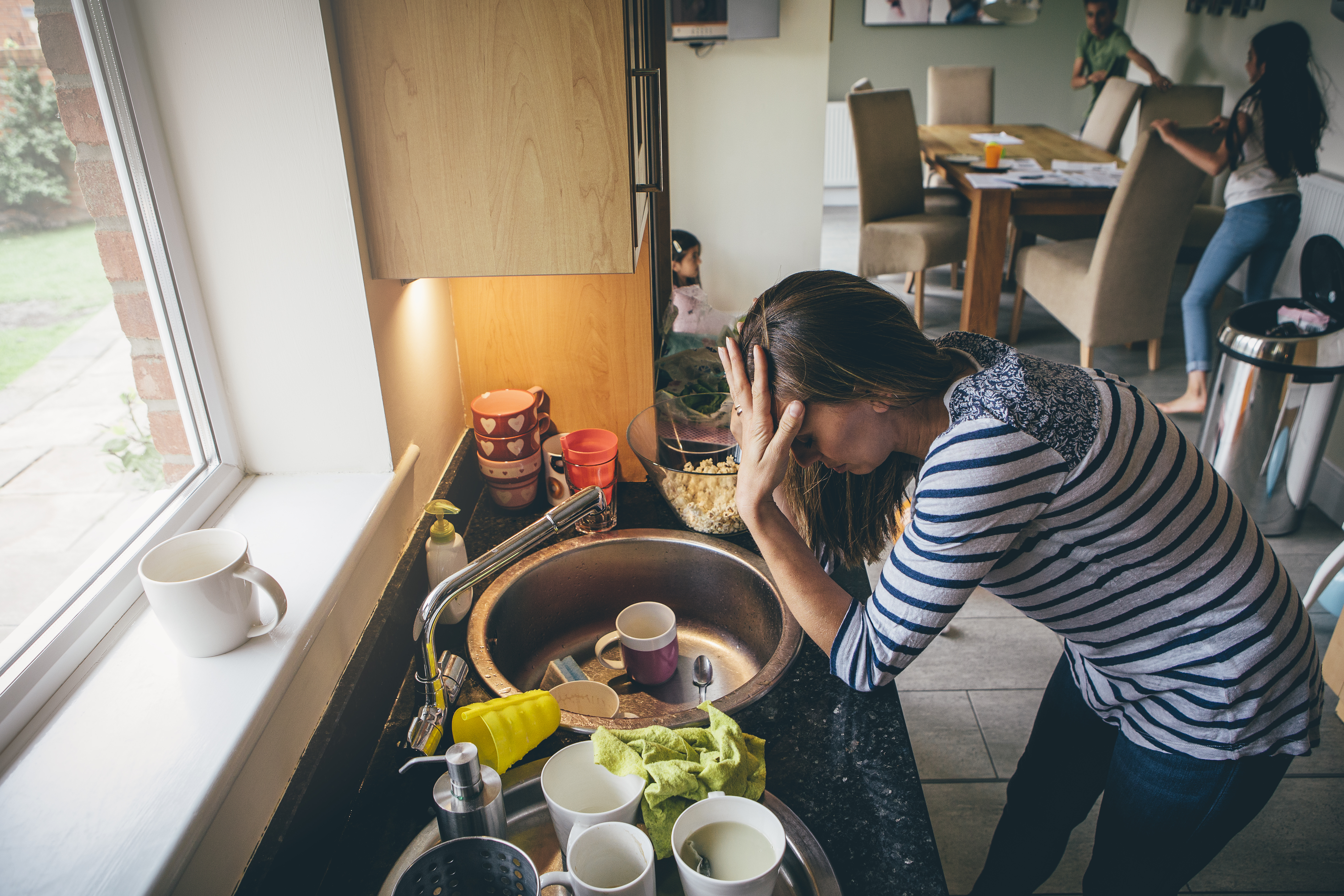 A woman leaning on a kitchen counter with her hand on her forehead | Source: Shutterstock
