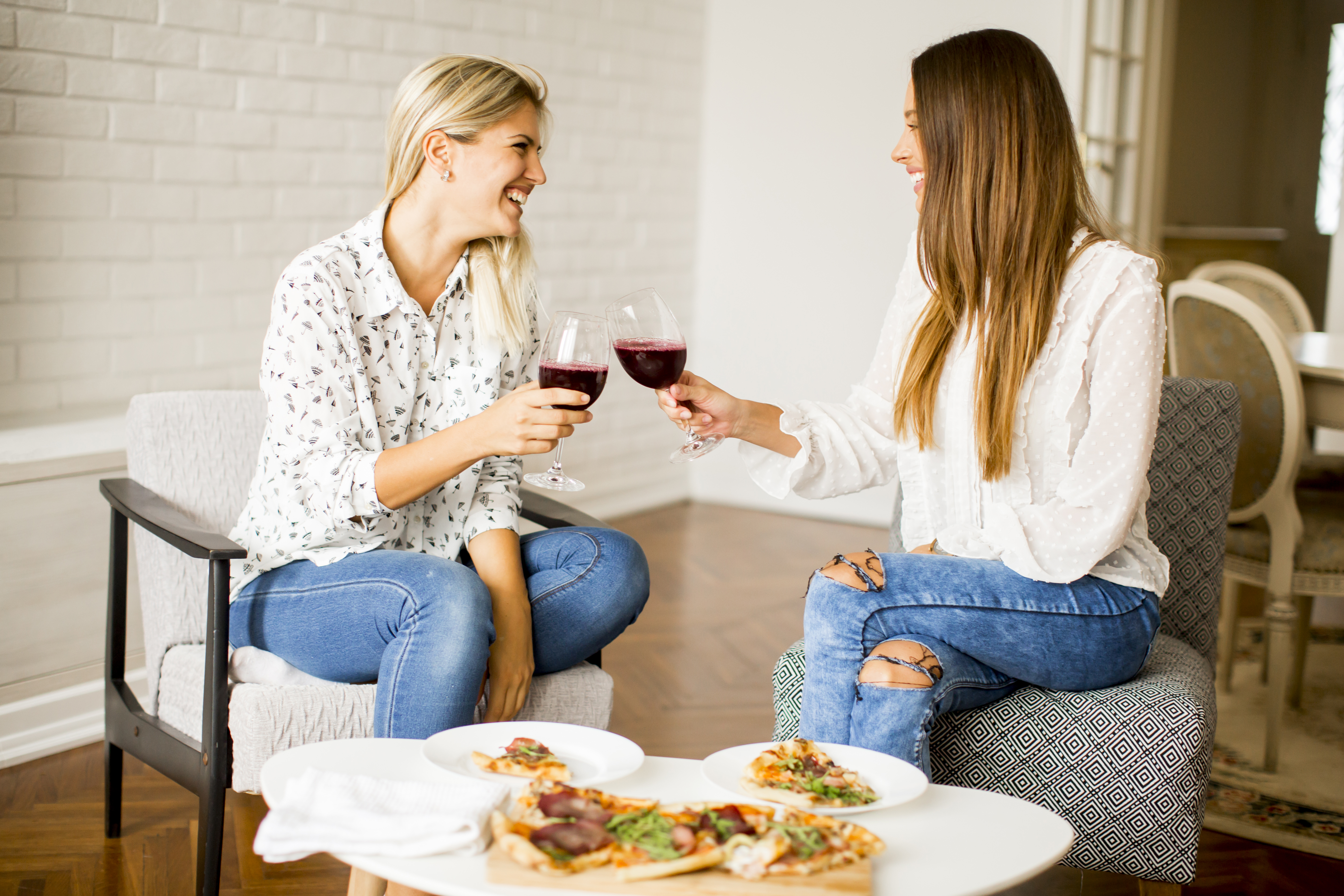 Pretty young women eating pizza and drink red wine | Source: Getty Images