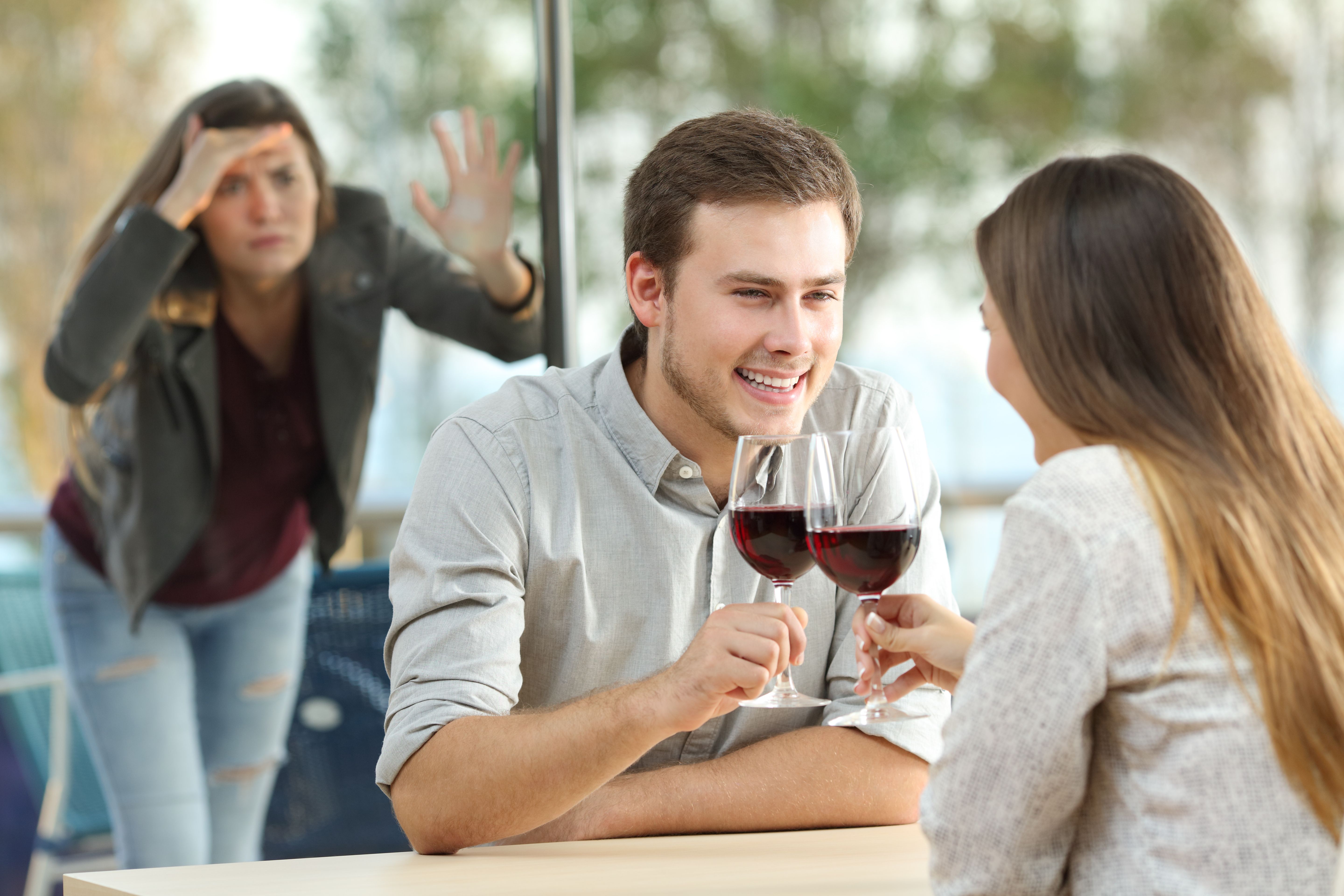 A woman peeping on a glass window at a couple having wine | Source: Shutterstock