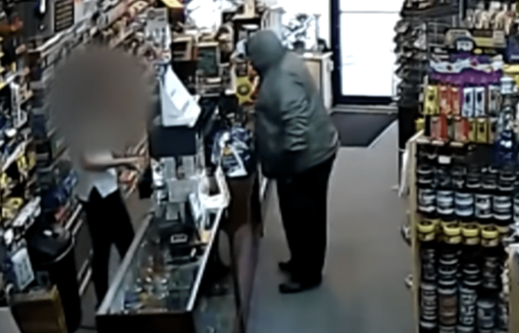 Disguised man with a gun standing in front of the cashier at a store as she opens the cash register.┃Source: youtube.com/CBS 17