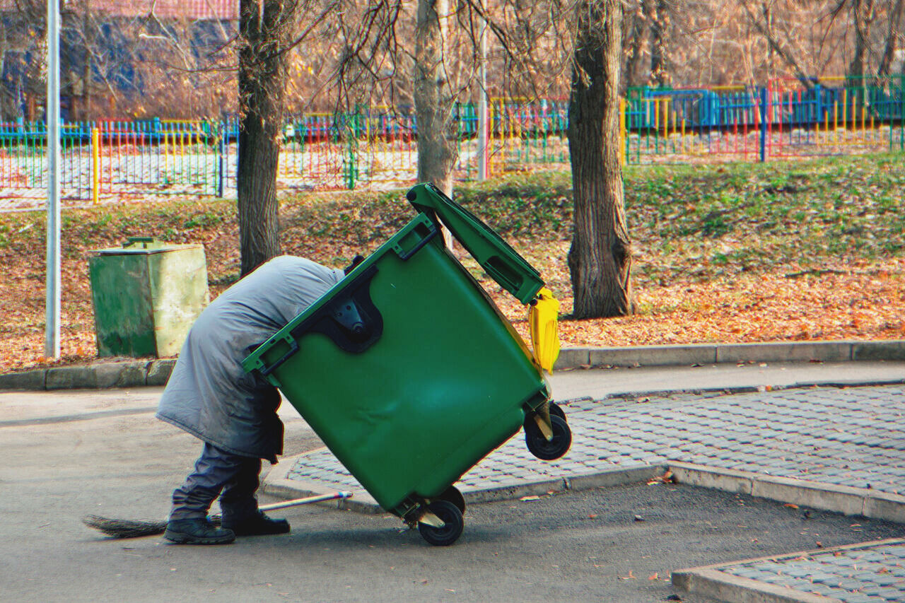 Homeless Man Digging Through Dumpster. | Source: Shutterstock