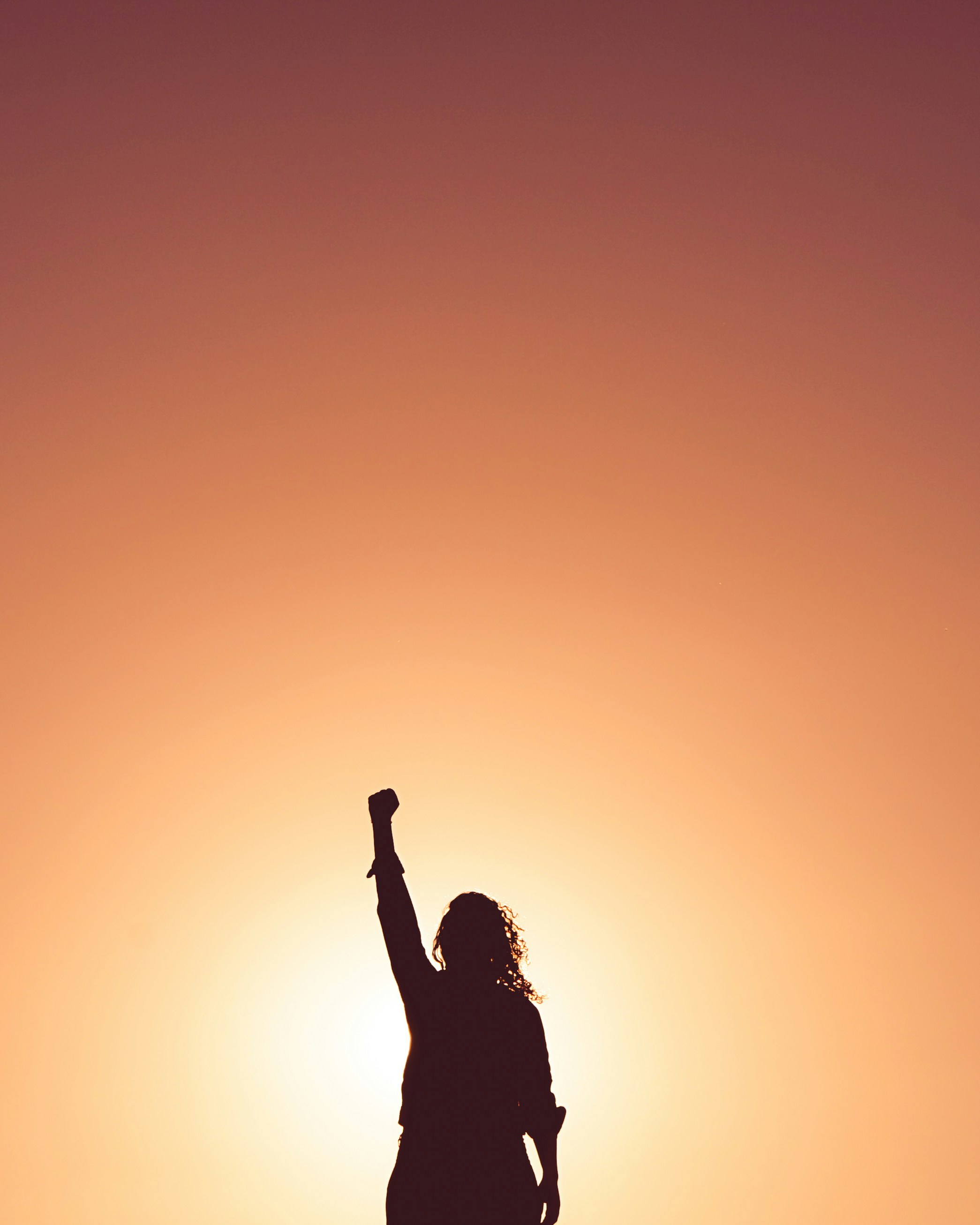 A silhouette of a person raising their arm in the air symbolizing power and strength | Source: Unsplash