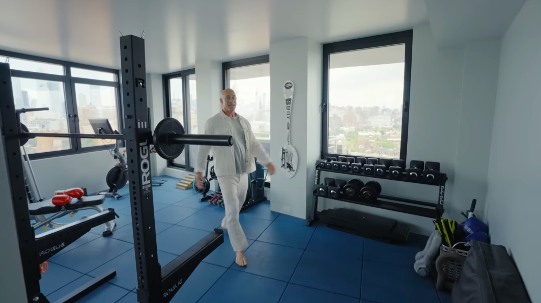 Christopher's idea of a happy space comes with barbells, dumbbells and plenty of sweat. The fully equipped home gym allows him to train without sacrificing the apartment's signature city views. | Source: YouTube/Architectural Digest