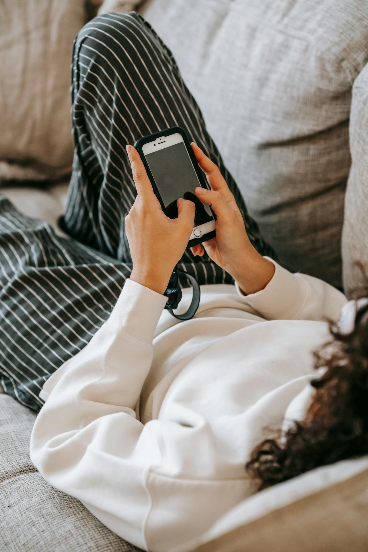A woman resting on the couch and using her phone | Source: Pexels
