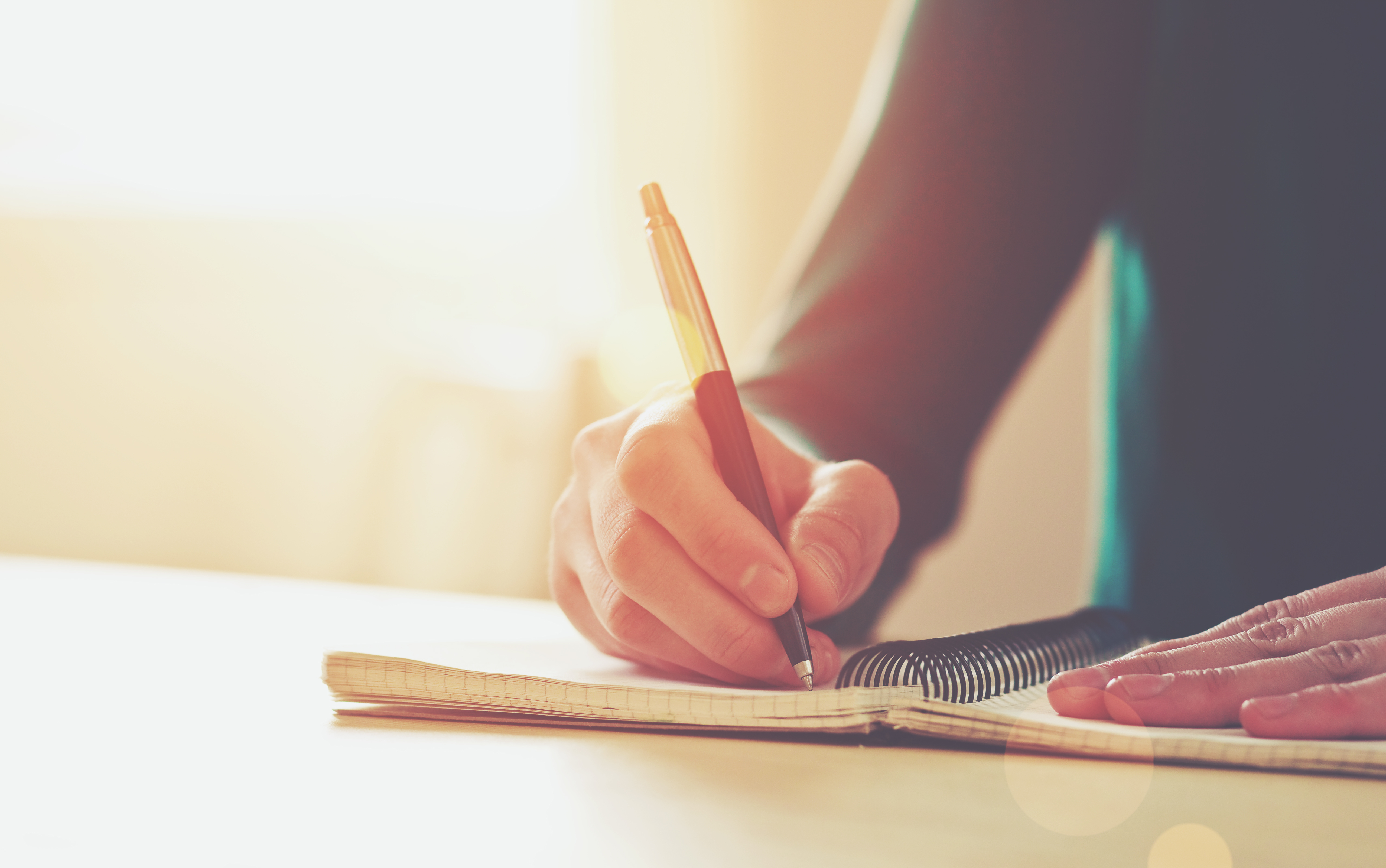 A hand scribbling on a notebook | Source: Shutterstock