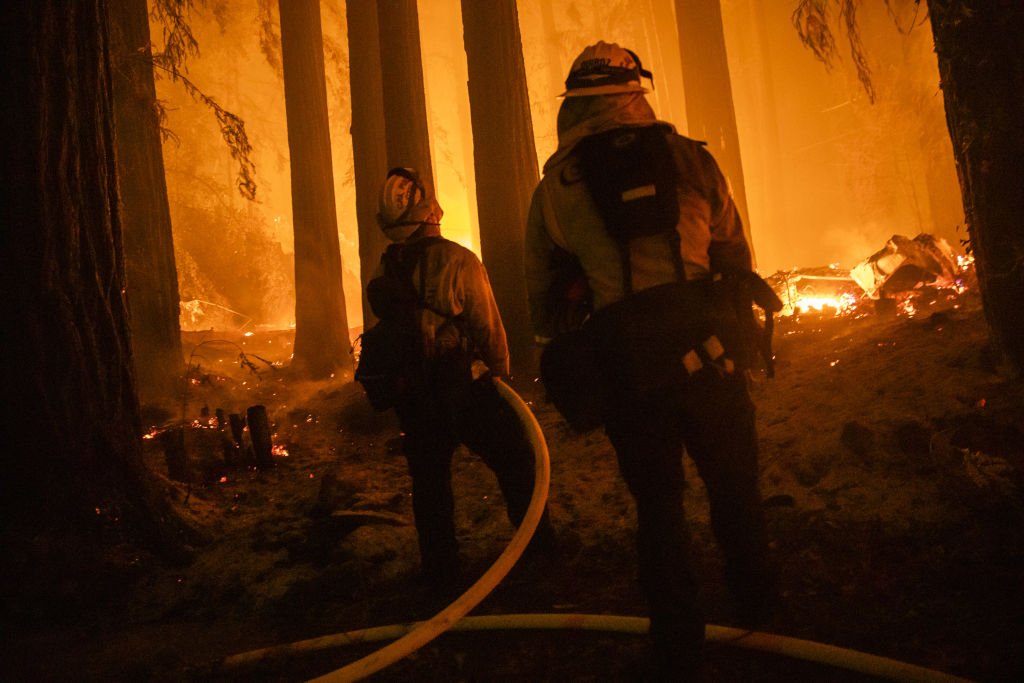 Firefighters with the Jamison Creek CDF station protect a home on Acorn Drive as flames approach during the CZU Lightning Complex fire | Photo: Getty Images