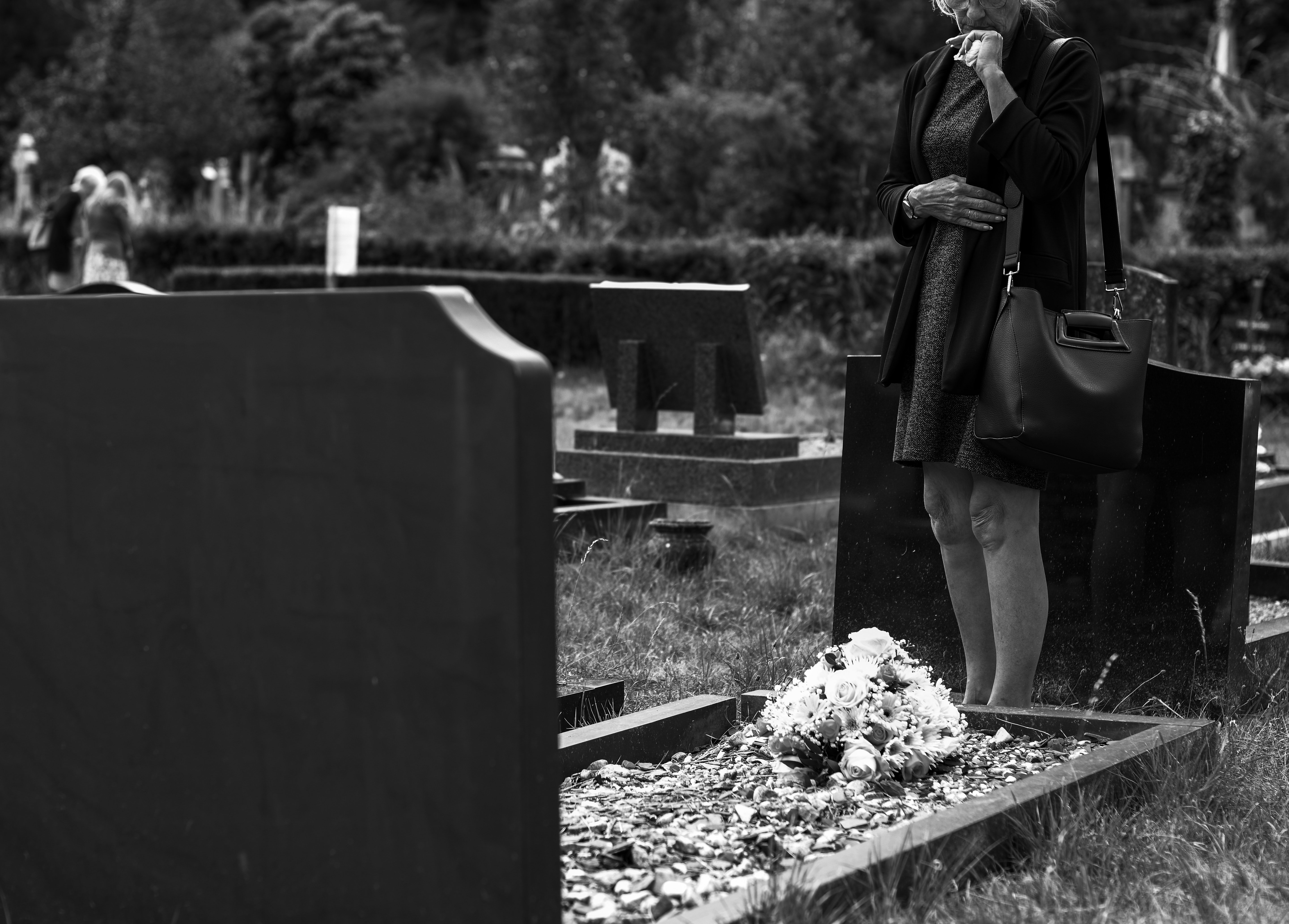 Woman grieving in front of a tombstone | Photo: Pexels