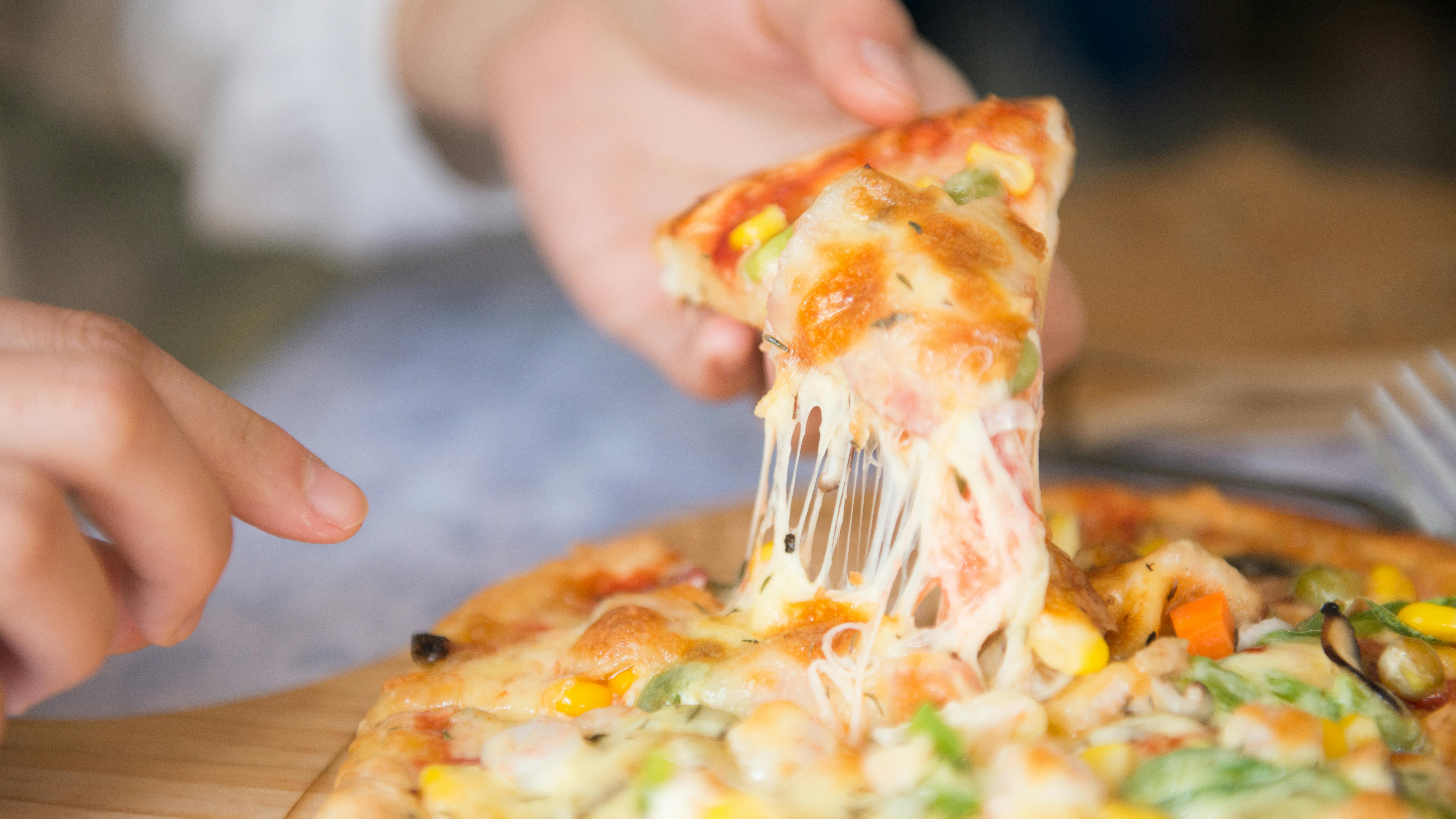 A person taking a slice of pizza | Source: Pexels