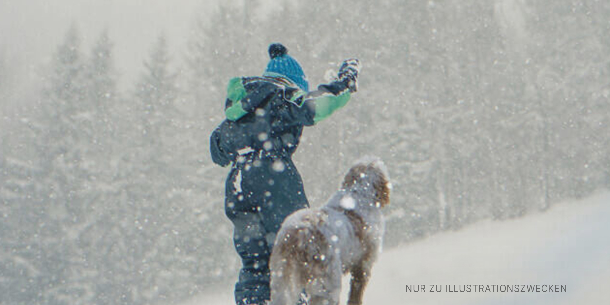 Ein Junge und ein Hund spielen im Schnee. | Quelle: Getty Images