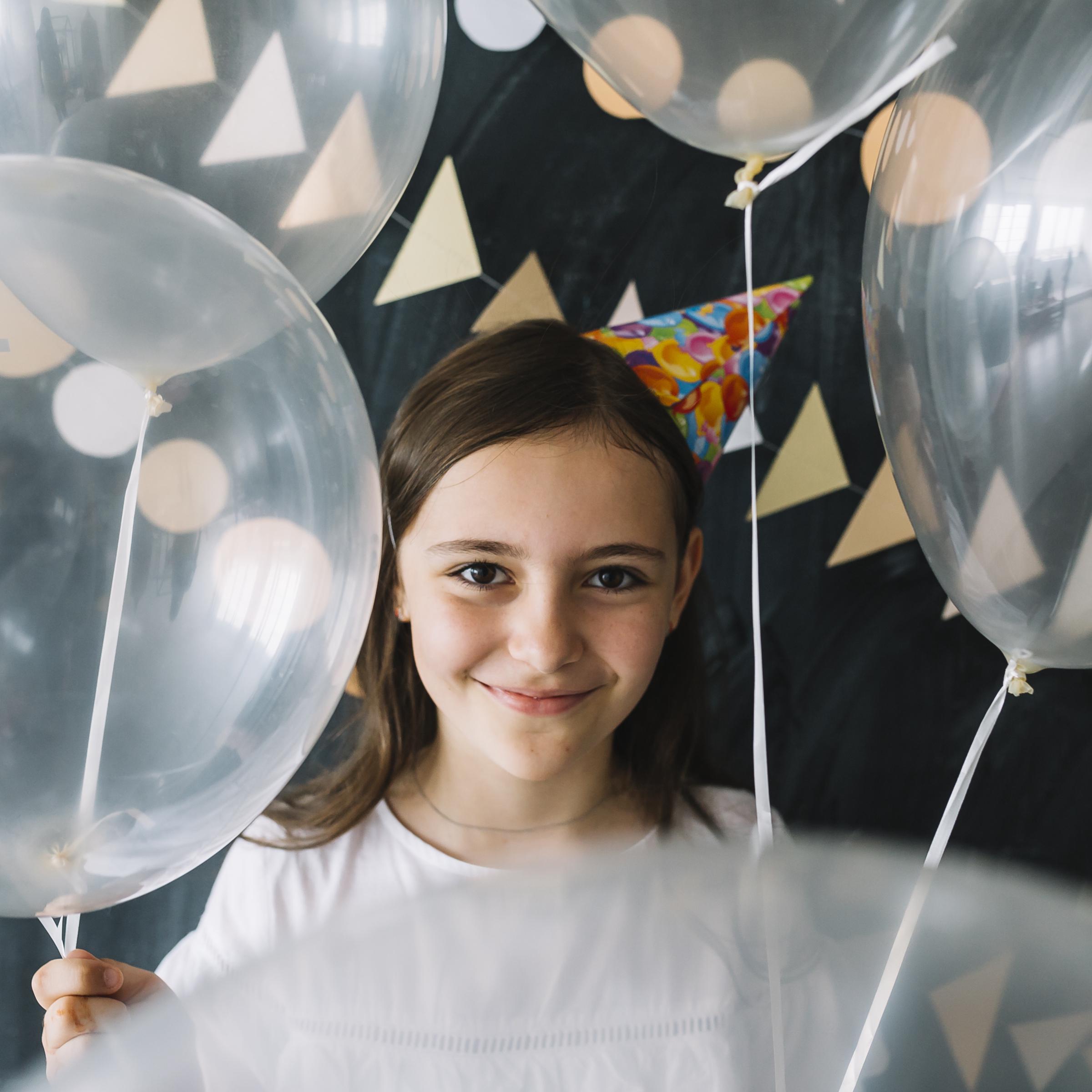 Little girl holding balloons at a party | Source: Freepik